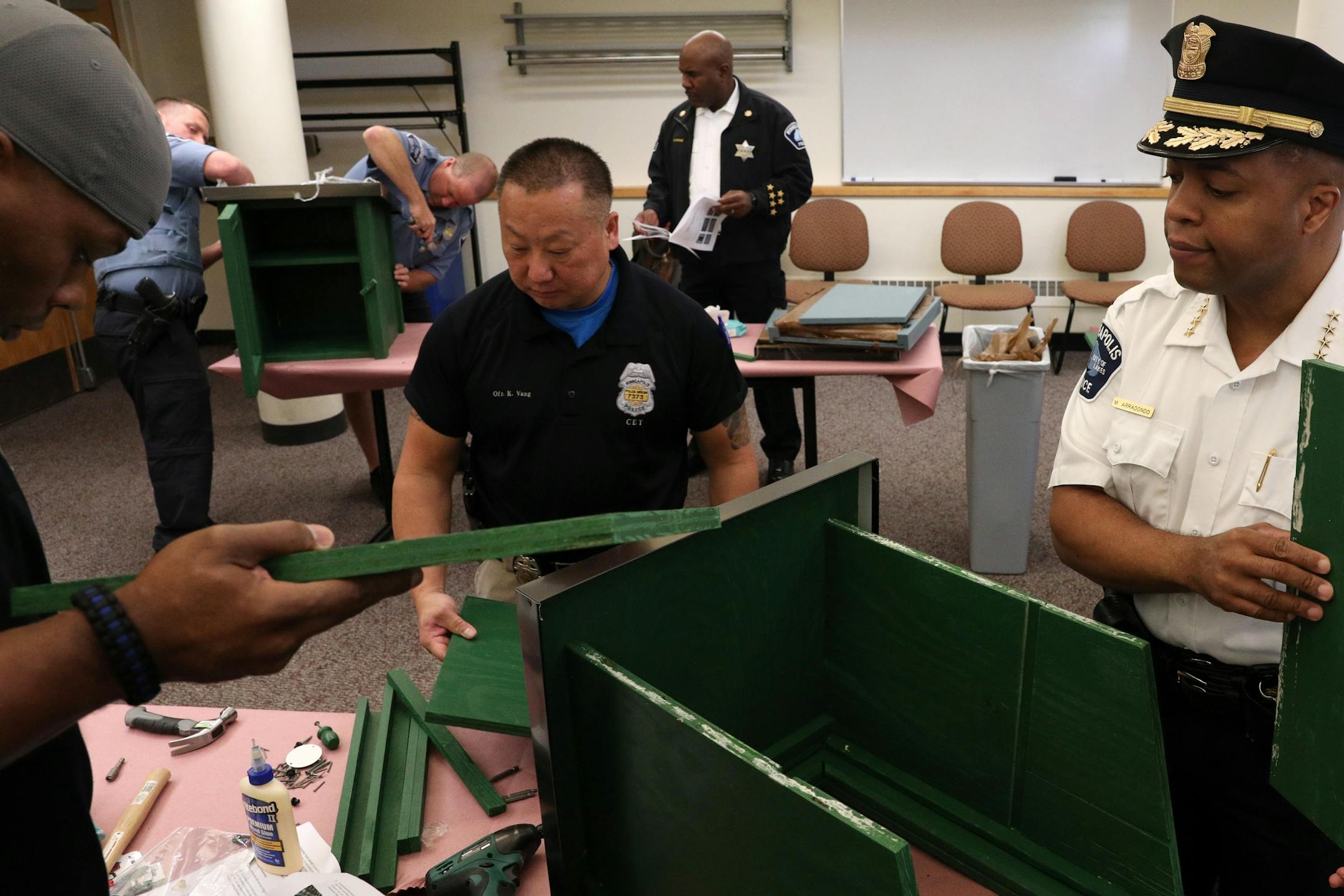 Police officers Troy Dillard, left, and Kou Vang, center, worked along with Police Chief Medaria Arradondo to build a free-standing Little Free Library Tuesday.