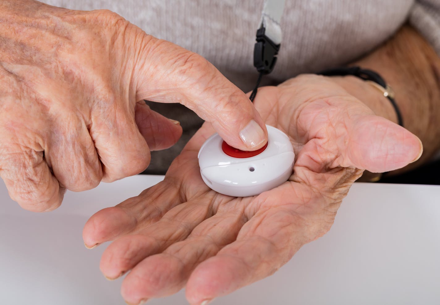 Close-up Of Senior Woman Pressing Alarm Button For Emergency