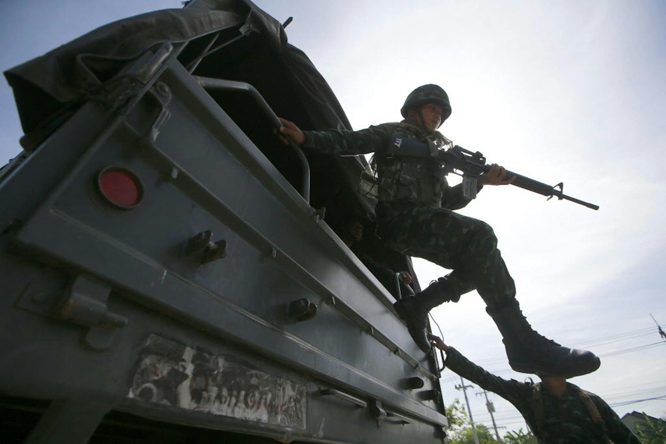 A Thai soldier jumps off a military truck after arriving at a pro-government rally site on the outskirts of Bangkok, Thailand Tuesday, May 20, 2014.