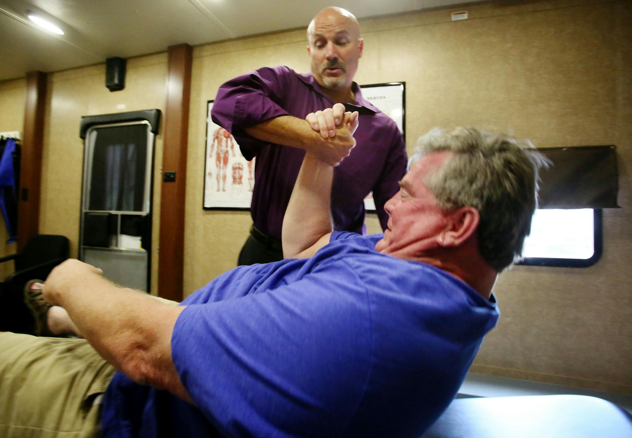 Ron Green, a U.S. Marine Veteran, who served during the Vietnam War era, gets help sitting up after getting treatment for foot problems by chiropractor Sheldon Osvold that had nearly prevented him from walking at Doug Huesby's non-profit, PainFree Patriots in the Living Word Christian Center parking lot Tuesday, July 28, 2015, in Brooklyn Park, MN. Green, who also has type II diabetes, said he was in tremendous pain with feet that were bleeding in June when he began treatment but that now his pa