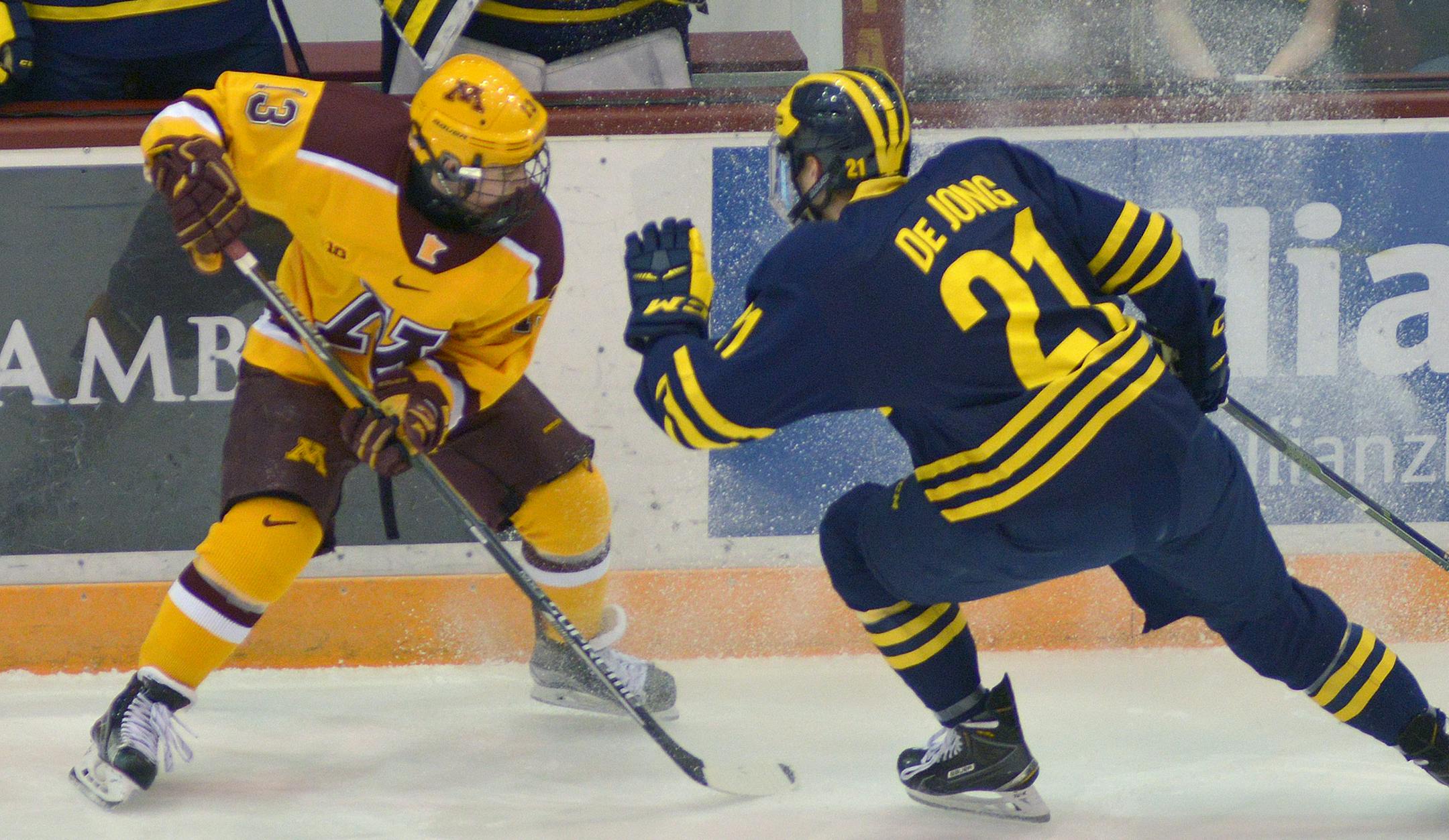 Minnesota left wing Taylor Cammarata battles with Michigan defenseman Nolan De Jong during the first period of the second game in the home series Friday, Feb. 26 at Mariucci Arena. ] (SPECIAL TO THE STAR TRIBUNE/BRE McGEE) **Taylor Cammarata (left, yellow, 13), Nolan De Jong *right, blue, 21)