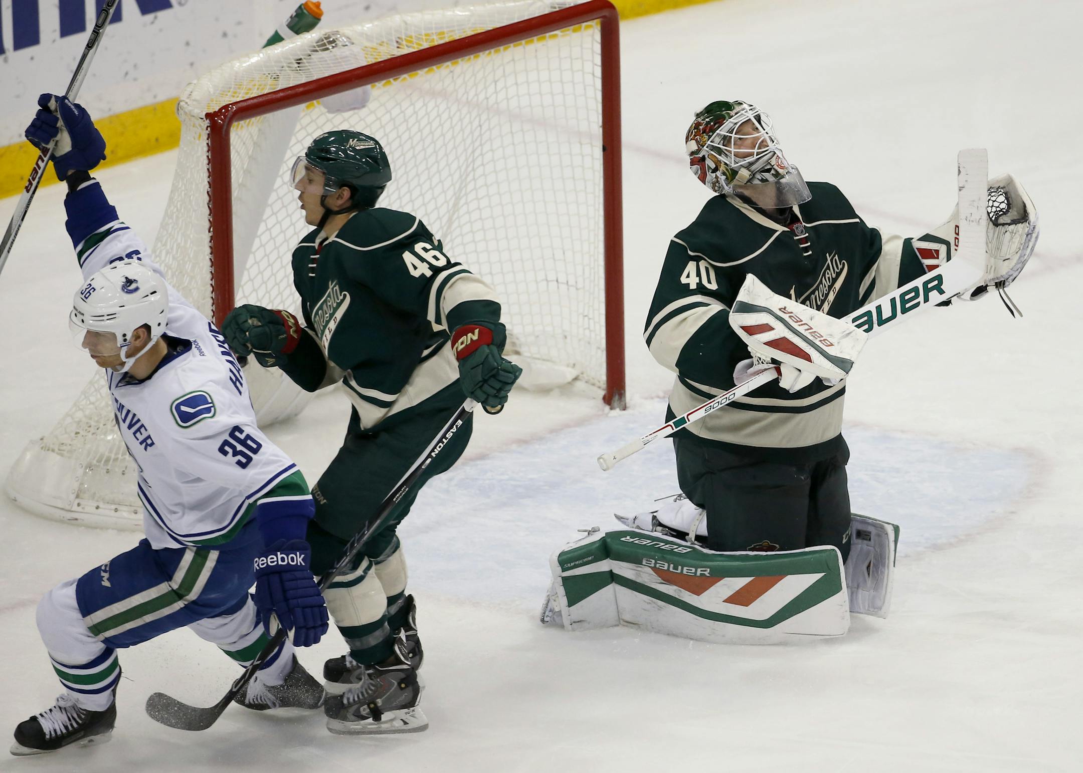 Minnesota Wild goalie Devan Dubnyk (40) reacts as Vancouver Canucks right wing Jannik Hansen (36), of Denmark, celebrates in front of Wild defenseman Jared Spurgeon (46)after scoring on Dubnyk during the third period of an NHL hockey game in St. Paul, Minn., Wednesday, Nov. 25, 2015. The Canucks won 3-2. (AP Photo/Ann Heisenfelt)