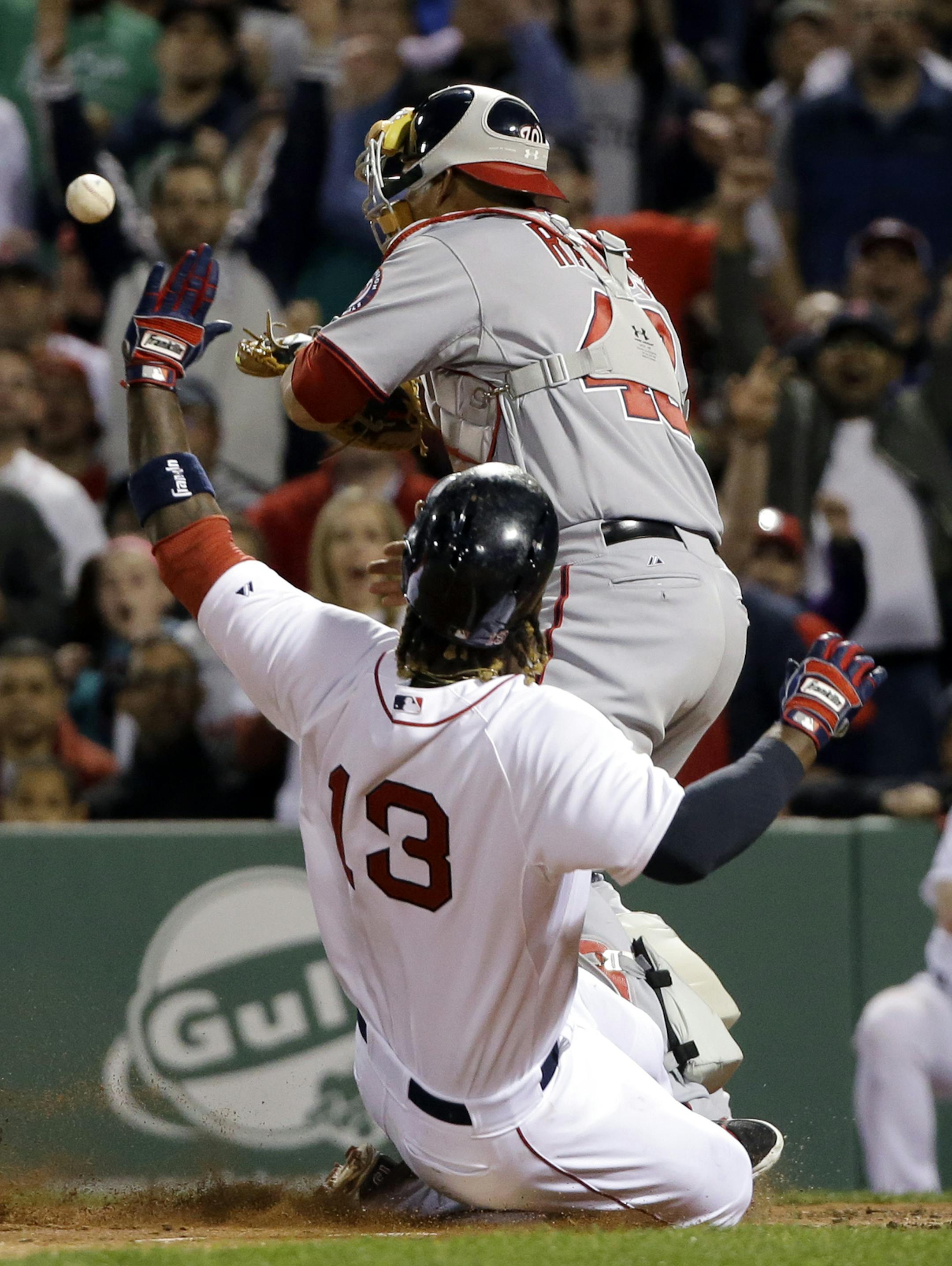 Boston Red Sox's Hanley Ramirez (13) slides into the plate to score on a fielding error by Washington Nationals relief pitcher Blake Treinen, as the ball gets away from Nationals catcher Wilson Ramos (40) in the seventh inning of a baseball game at Fenway Park in Boston, Tuesday, April 14, 2015. (AP Photo/Elise Amendola)