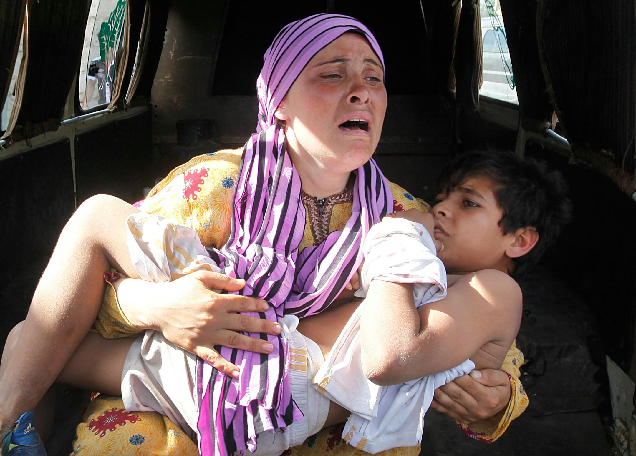 A Syrian woman, cries as she carries her injured son who was shot in his hand by the Syrian border guard in May.