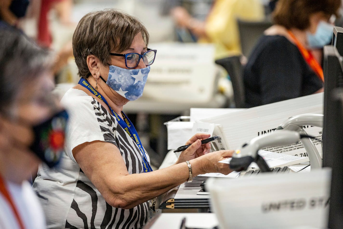 An election worker scans a ballot while doing the first check of the signature while processing ballots at the Pima County Elections Office located in Tucson, Ariz., Wednesday, Nov. 4, 2020.