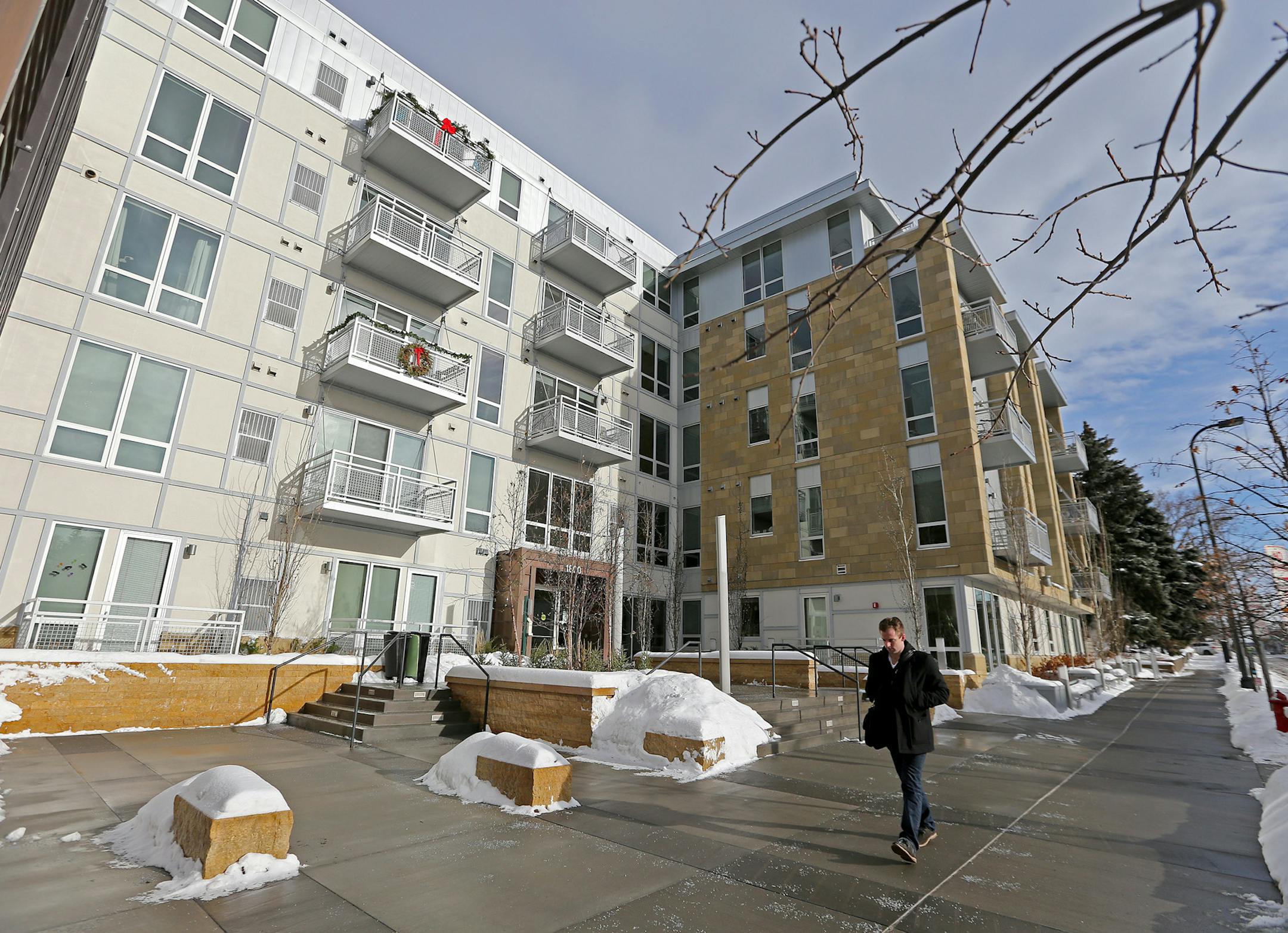 A walker made his way down a sidewalk in front of an apartment building that is the site of controversy, Friday, December 27, 2013 in Minneapolis, MN. The city of Minneapolis is suing the owner of an Uptown luxury apartment building over what the city says is the illegal discharge of groundwater into the lagoon between Isles and Calhoun.The water is being pumped out to keep the building's two stories of underground garage dry. Critics say the 55-degree groundwater is making the ice thin and dang