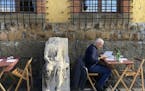 An ancient Roman marble statue sat among tables of a restaurant in Rome, where travelers may be able to return soon without quarantining.