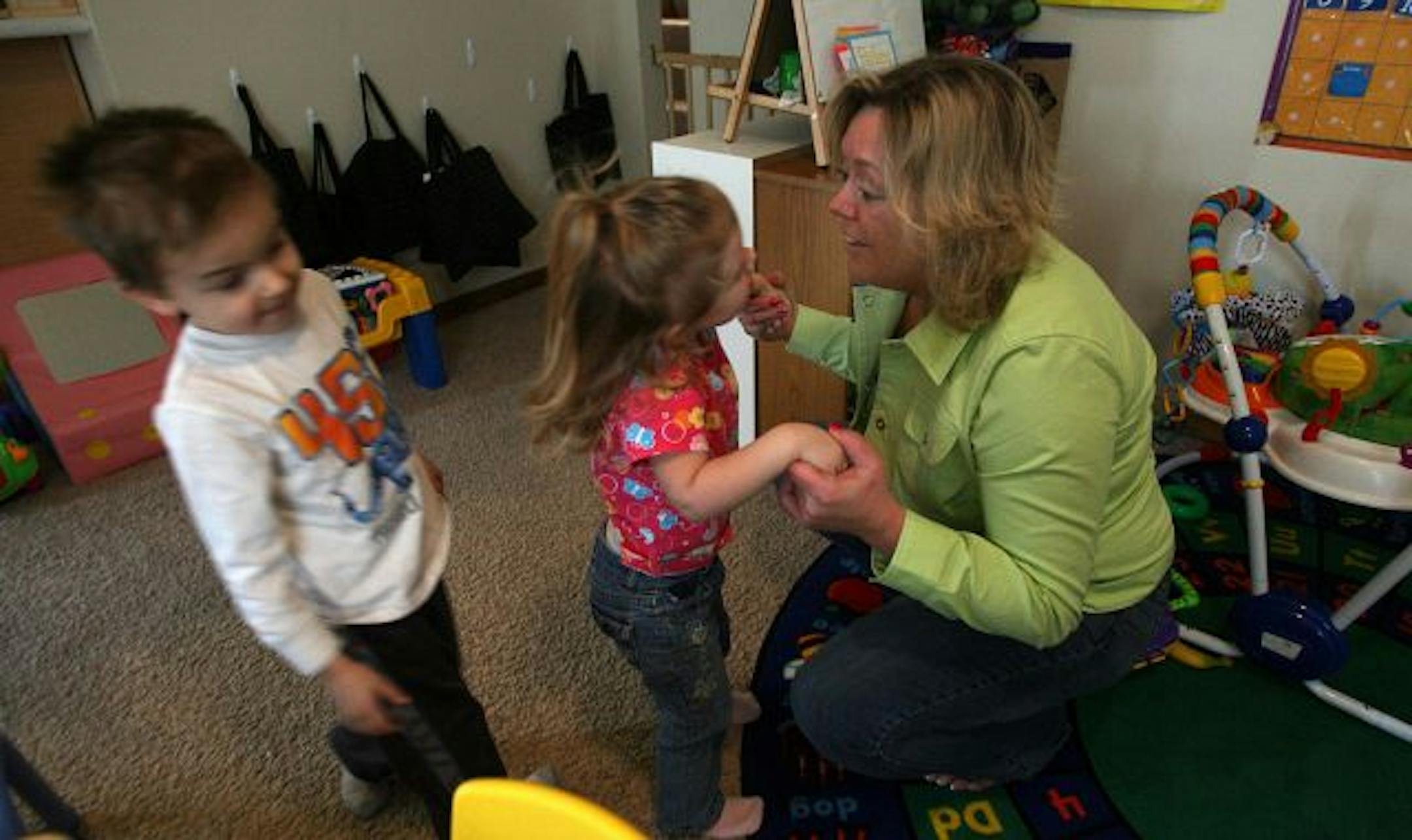 Day care provider Penny Shepherd played with Anna Baar and Andrew Renstrom at her home in White Bear Lake. Some care providers have found part-time jobs to pick up the slack.
