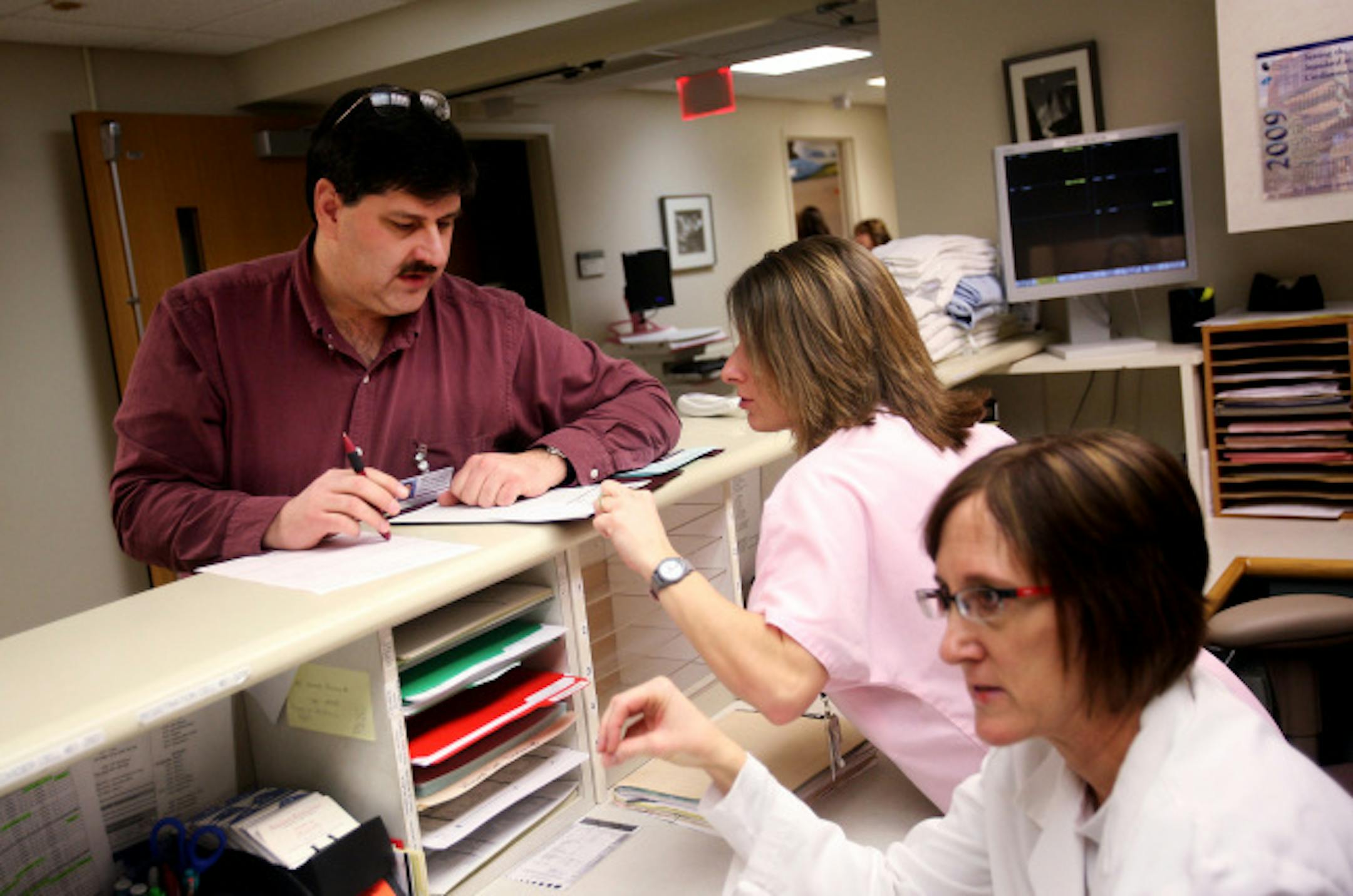 Physician assistant Mark Ross discussed a patient chart with Christa Rider, center, a registered nurse. Ross and Rhonda Wallace, right, are two of the physician assistants who staff the emergency room at Waseca Medical Center.