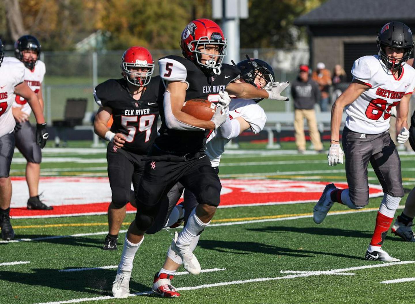 Elk River's Jack Sumstad stiff arms a Duluth East defender. Sumstad scored on a 63 yard run in the second quarter to give the Elks a 36-12 lead. Photo by Cheryl A. Myers, SportsEngine