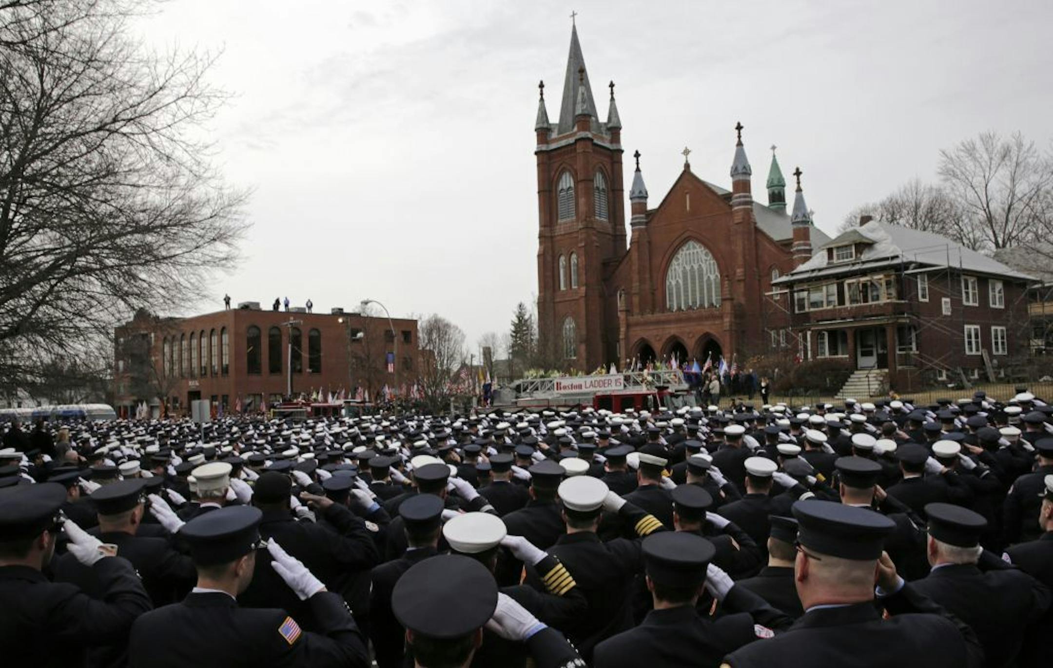 Firefighters salute as the casket of Boston Fire Lt. Edward Walsh is lowered from Engine 33 as it arrives outside the Church of Saint Patrick in Watertown, Mass., Wednesday, April 2, 2014.