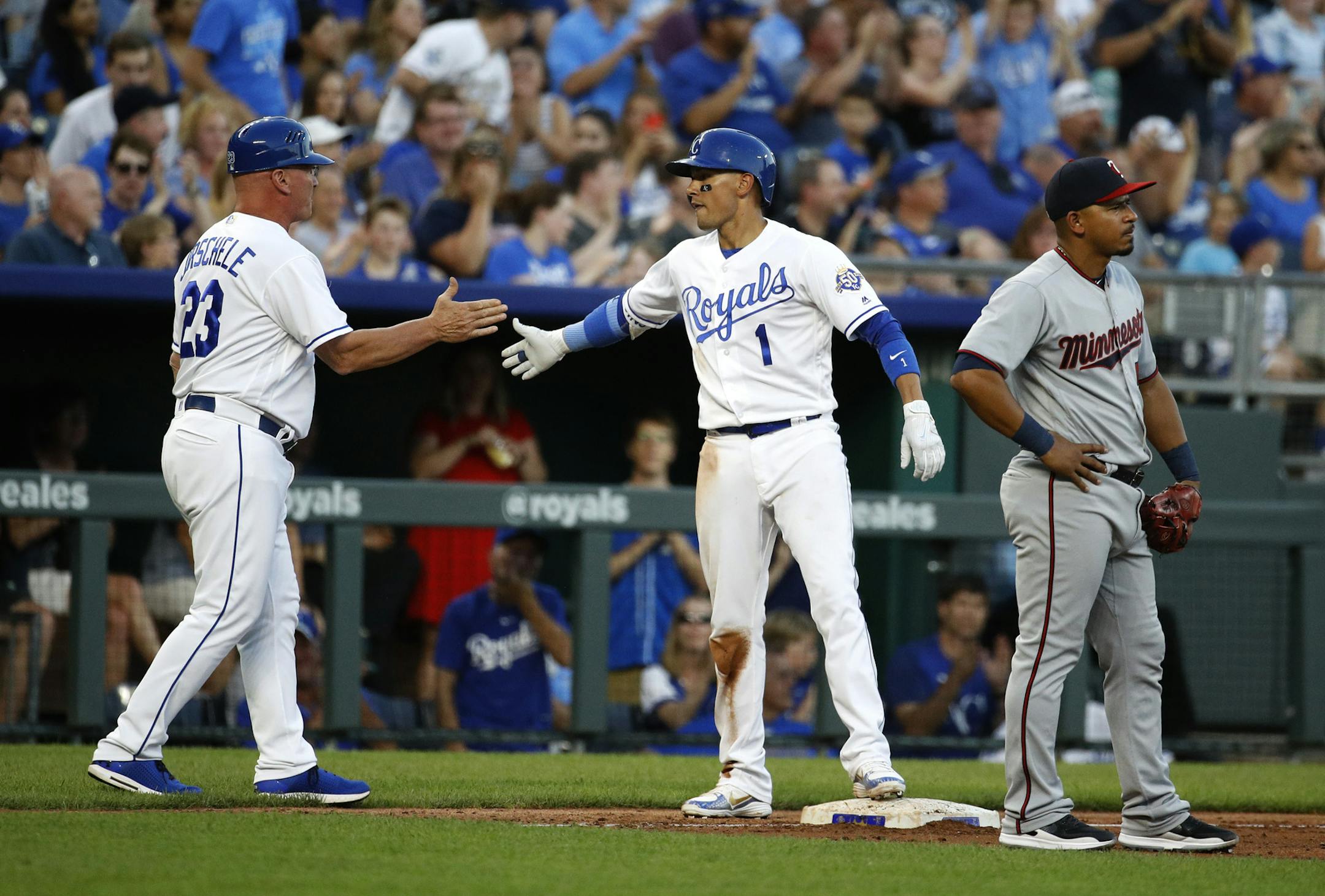 Kansas City Royals' Ryan Goins (1) celebrates with third base coach Mike Jirschele after hitting a two-run triple during the second inning of a baseball game against the Minnesota Twins on Wednesday, May 30, 2018, in Kansas City, Mo. (AP Photo/Charlie Riedel)