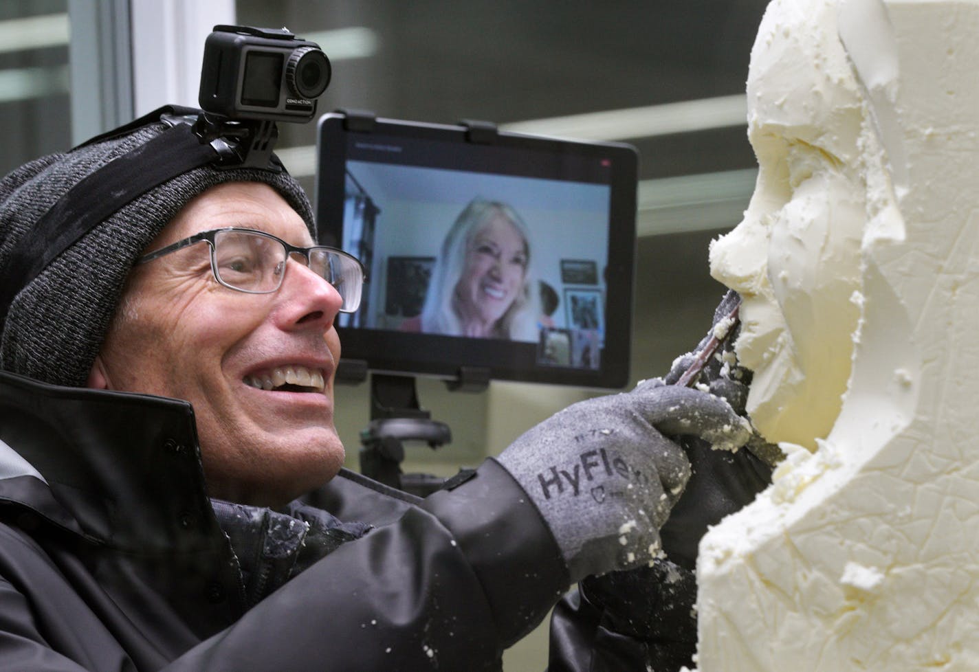 Longtime butter-princess sculptor Linda Christensen communicated via FaceTime to her apprentice, Gerry Kulzer, who was working on the butter sculpture of the 2020 Princess Kay of the Milky Way Brenna Connelly of Byron, MN. (Special precautions had to be taken including glass wall between Kulzer and Connelly, mask worn by Connelly and no fairgoers to watch in the dairy building. When Kulzer worked on Connelly's mouth and nose, she had to step out of the refrigerated studio and Kulzer would see he