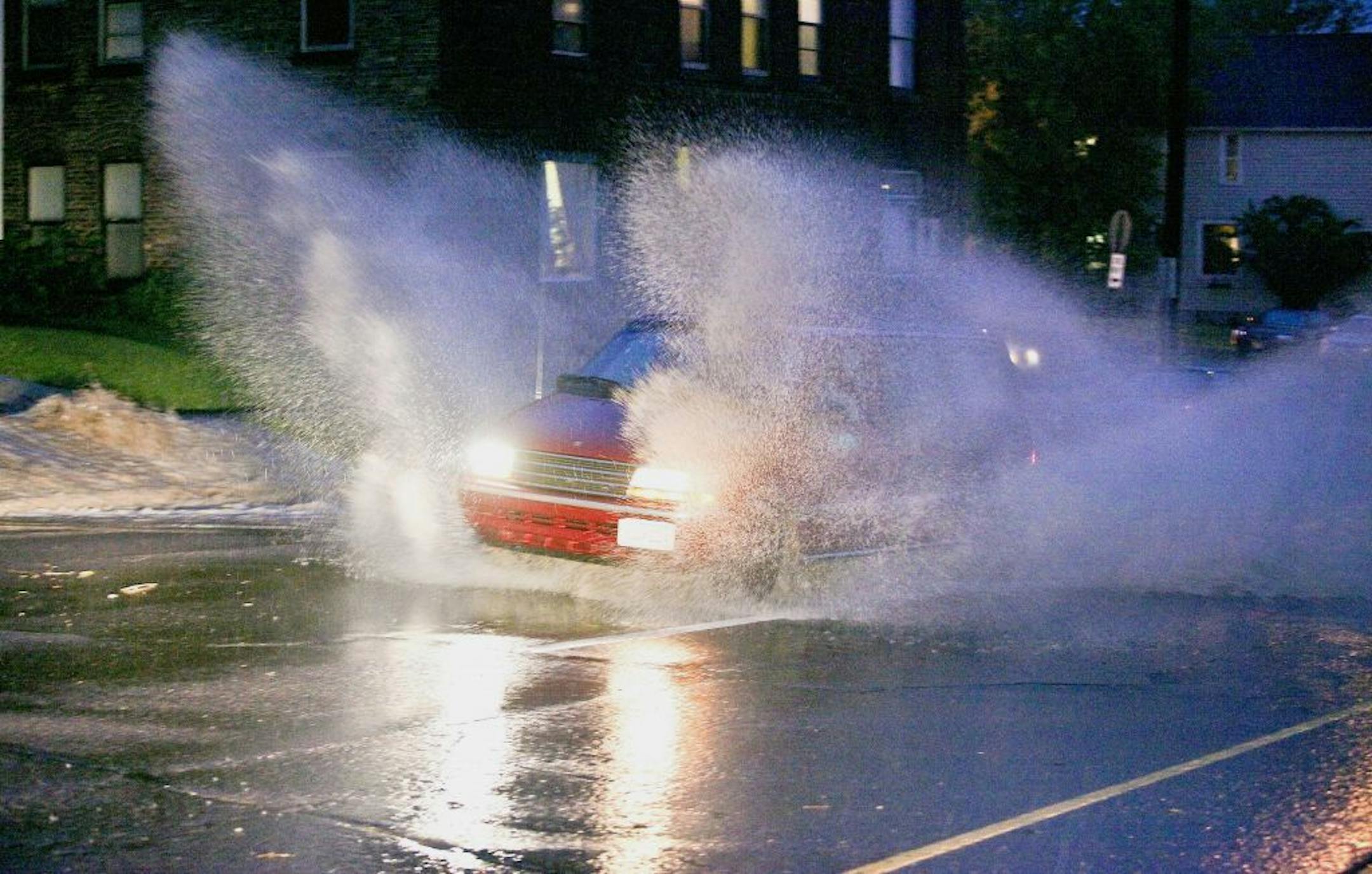 A minivan throws up walls of water while charging through flood waters on the 600 block of East Third Street in Duluth, Minn., Tuesday, June 19, 2012, after heavy rains hit the area.