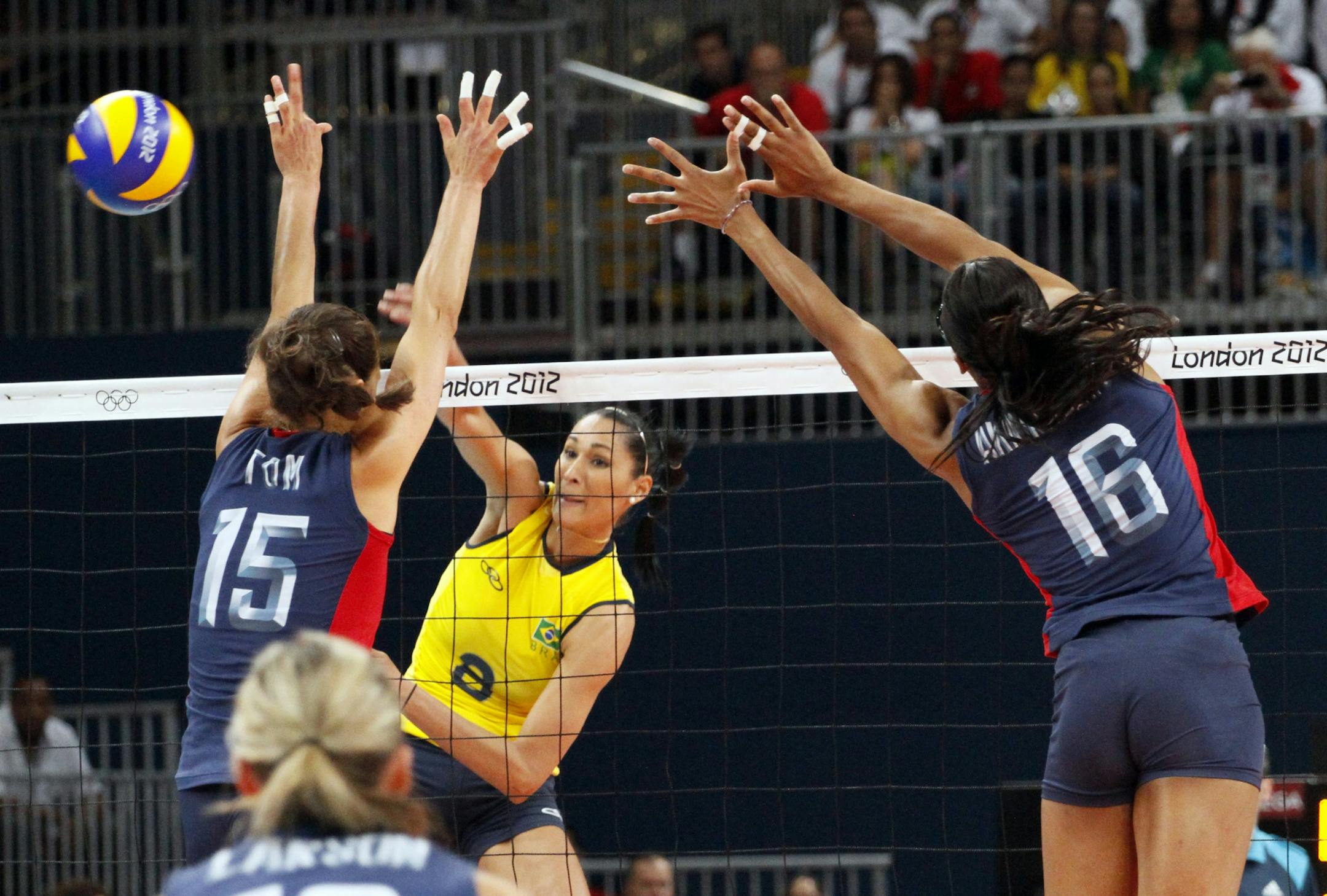 The United States' Logan Tom (15) and Foluke Akinradewo (16) try to block a shot from Jaqueline Carvalho of Brazil the women's indoor volleyball finals at the Summer Olympics in London, England, on Saturday, August 11, 2012. Brazil captured the gold medal with a 3-1 victory.