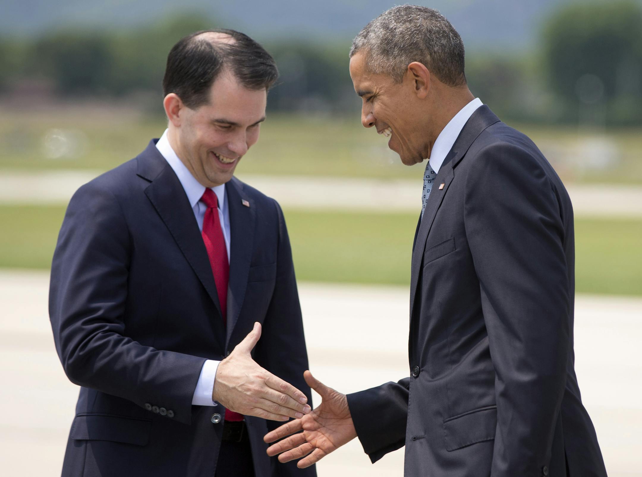 President Barack Obama is greeted by Wisconsin Gov. Scott Walker as he arrives on Air Force One at La Crosse Regional Airport, Thursday, July 2, 2015, in La Crosse, Wis. The president is en route to the University of Wisconsin at La Crosse where he is to speak about the economy and promote a proposed Labor Department rule that would make more workers eligible for overtime. (AP Photo/Carolyn Kaster)