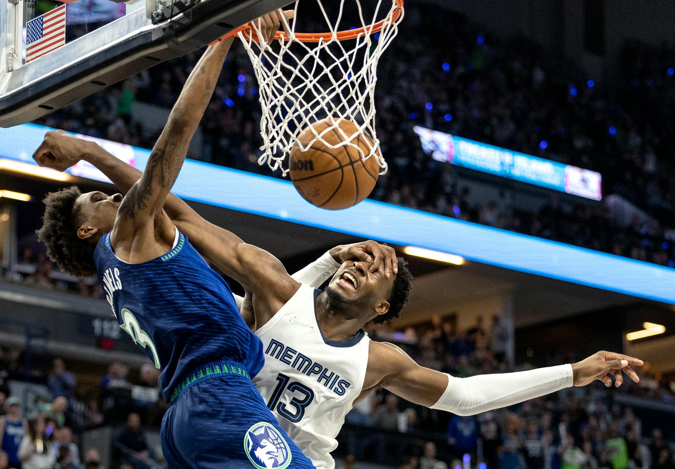 Jaden McDaniels (3) of the Minnesota Timberwolves dunks the ball while defended by Jaren Jackson Jr. (13) of the Memphis Grizzlies in the fourth quarter.