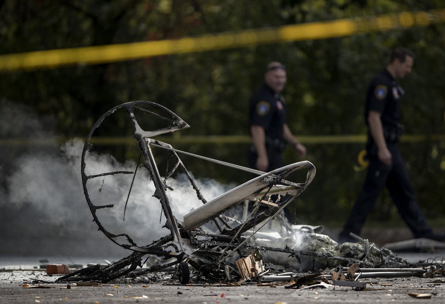 Emergency crews walk by the wreckage of a small plane that crashed in the parking lot of Resurrection Life Church in Eden Prairie.