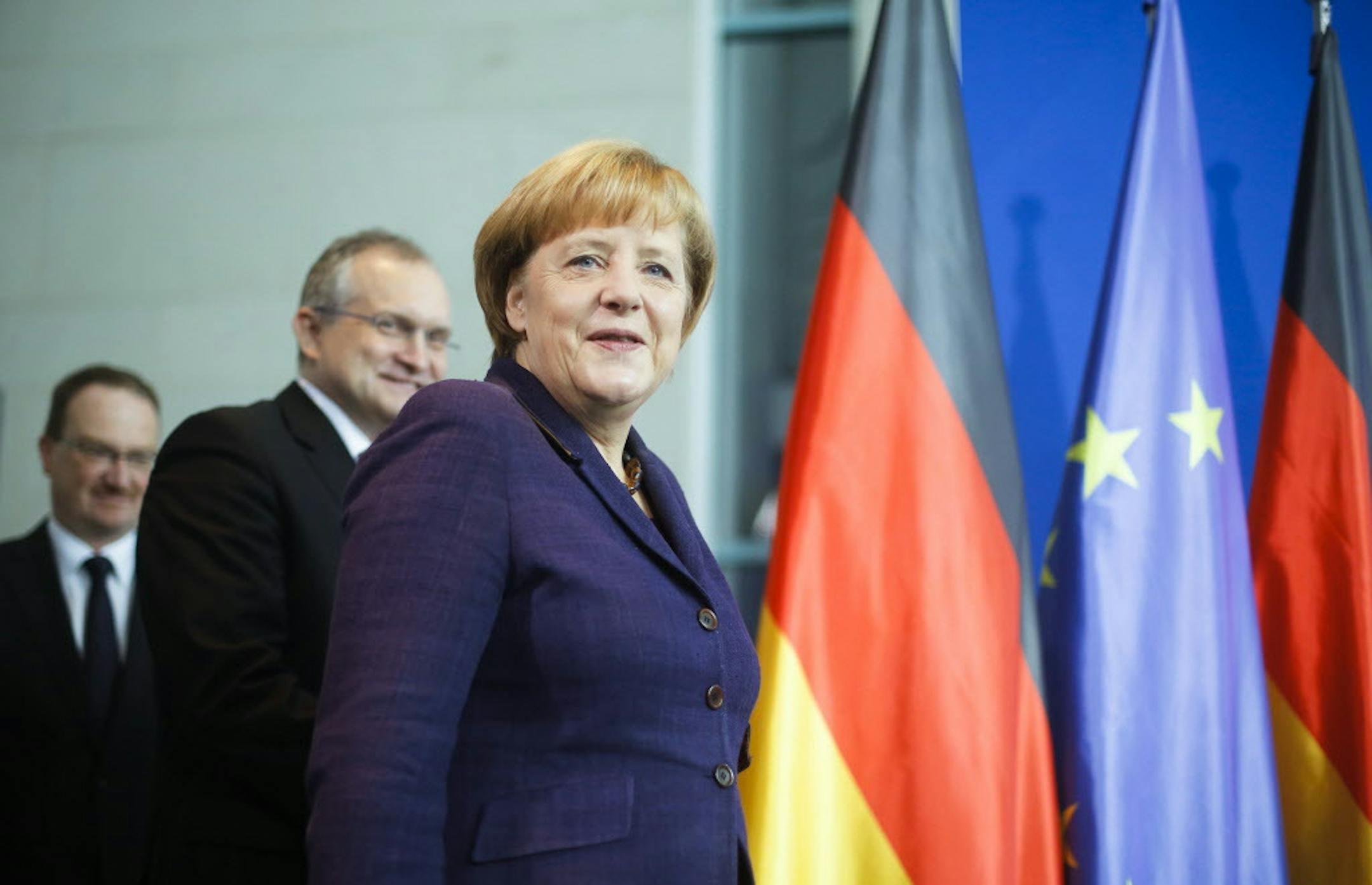 German Chancellor Angela Merkel is followed by economy advisers Lars Feld, left, and Christoph Schmidt, center, as they arrive for the hand-over ceremony of the prognosis for Germany's economy in the upcoming year at the chancellery in Berlin, Wednesday, Nov. 13, 2013. (AP Photo/Markus Schreiber)