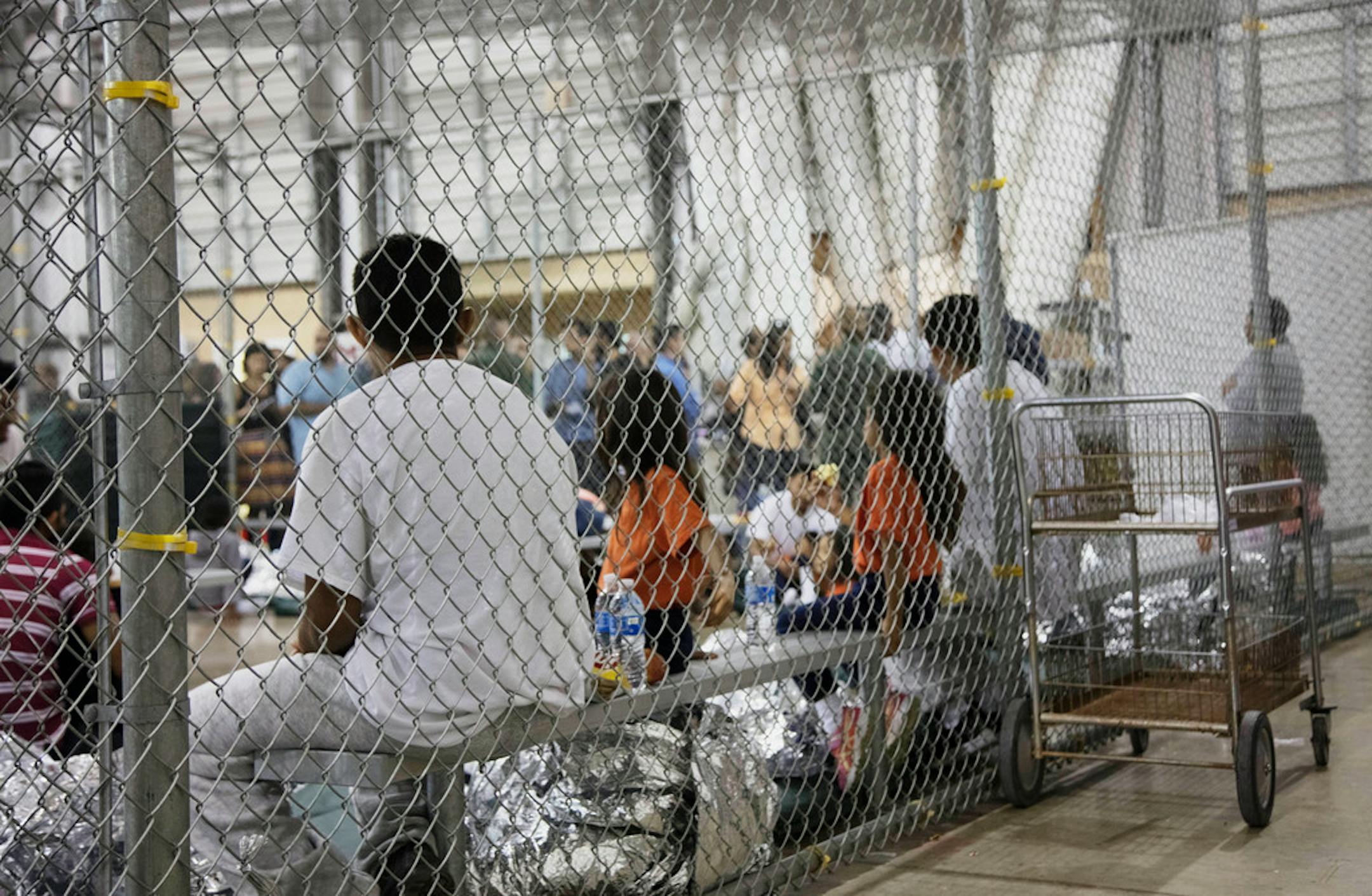 FILE - In this June 17, 2018, file photo, provided by U.S. Customs and Border Protection, people who have been taken into custody related to cases of illegal entry into the United States, sit in one of the cages at a facility in McAllen, Texas. Advocates were shocked to find an underage mom and her tiny, premature newborn daughter huddled in a Border Patrol facility this week in what they say was another example of the poor treatment immigrant families receive after crossing the border. The moth