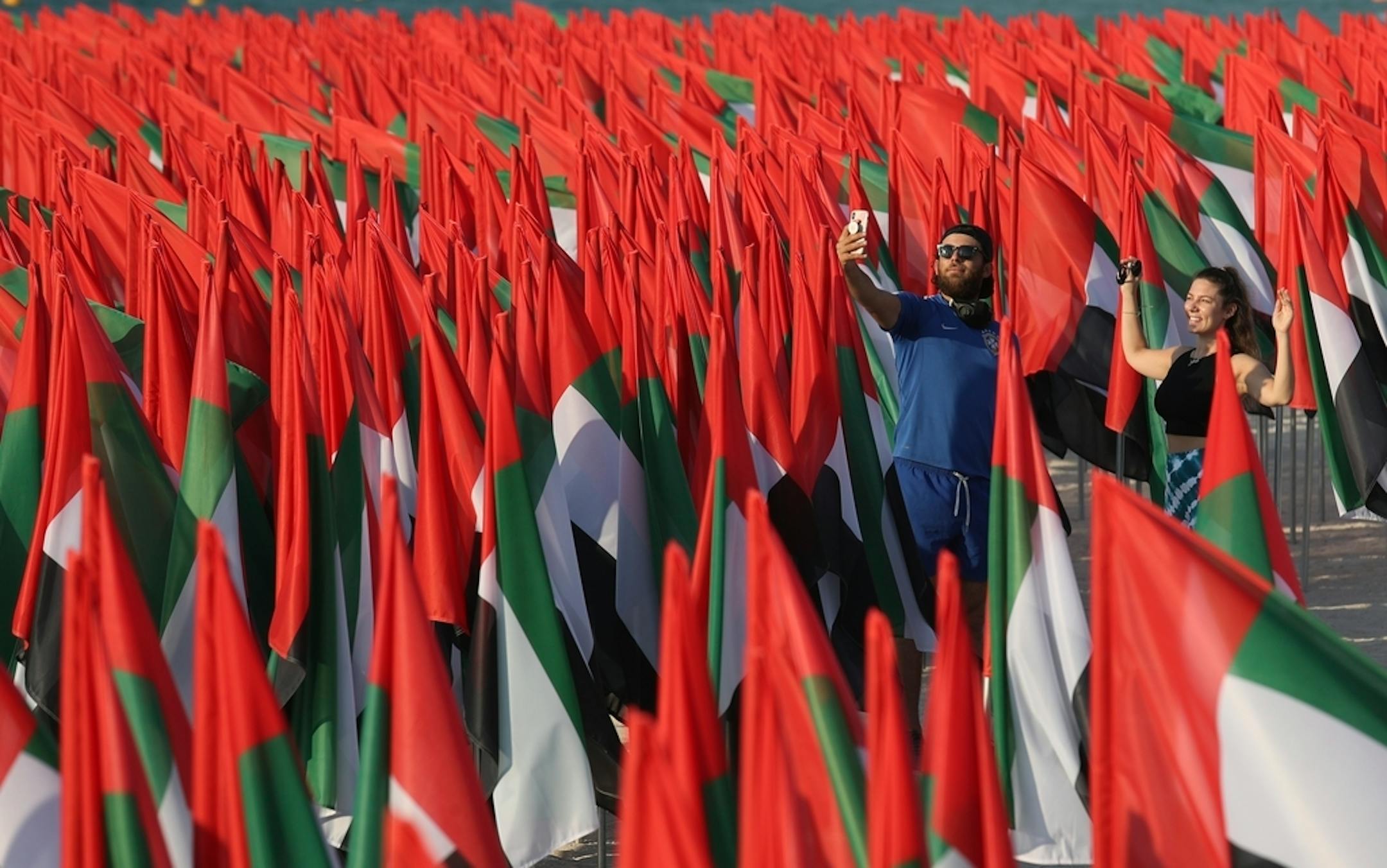 A man takes a selfie among UAE national flags set up to celebrate the country's Flag Day, in Dubai, United Arab Emirates, Tuesday, Nov. 3, 2020. (AP Photo/Kamran Jebreili)