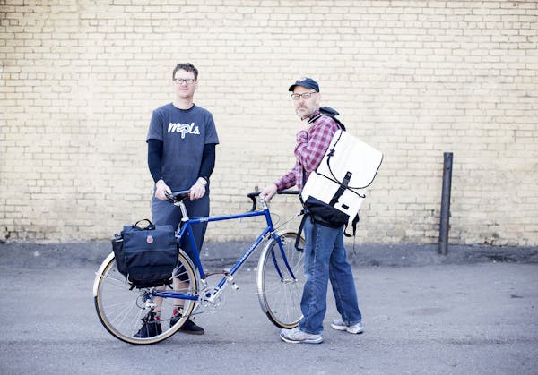 Banjo Brothers owners Eric Leugers, left, and Mike Vanderscheuren pose with two of their popular panniers in a Minneapolis alley April 21, 2014. (Cour