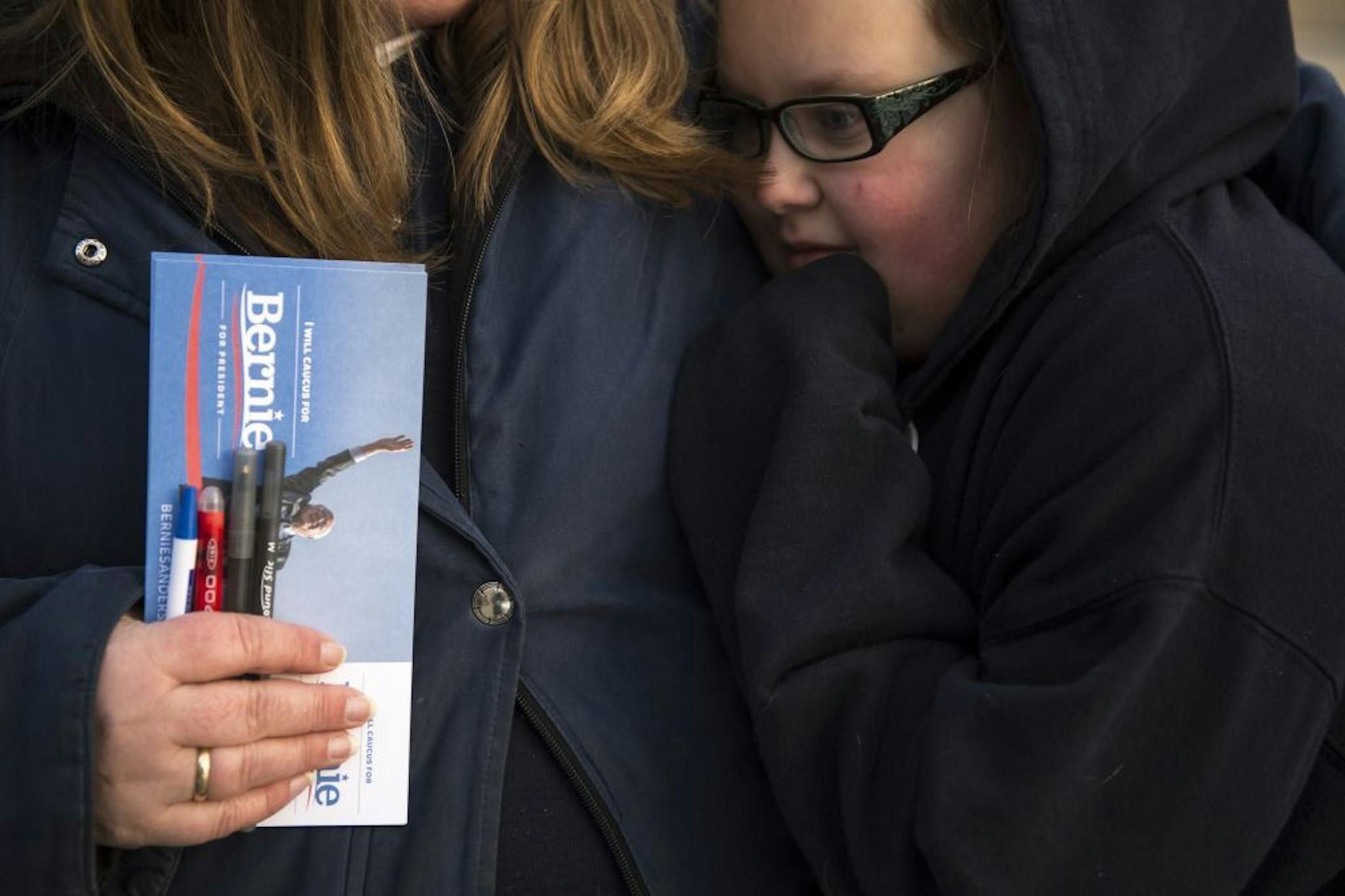 Eva Carlson, 12, warmed up against her mother, Jill Carlson, of Keewatin, as Jill volunteered Friday morning at the Bernie Sanders event at Hibbing High School.