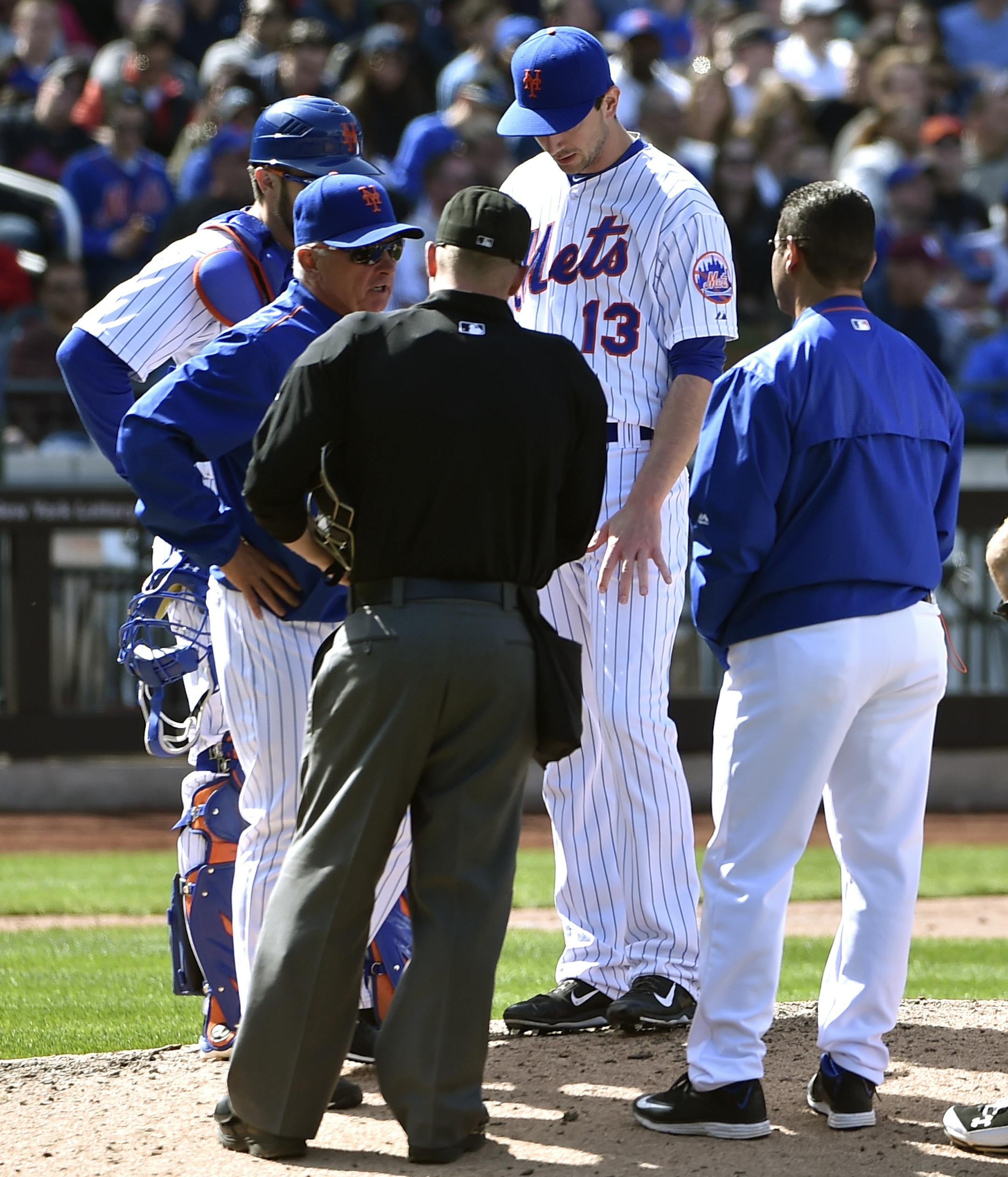 New York Mets catcher Travis d'Arnaud, manager Terry Collins, home plate umpire Sean Barber and a Mets trainer discuss relief pitcher Jerry Blevins' (13) injured left forearm in the seventh inning of a baseball game at Citi Field on Sunday, April 19, 2015, in New York. Blevins left forearm was fractured by a line drive by Miami Marlins Dee Gordon. d'Arnaud later left the game when he fractured his right hand after being hit by a pitch thrown by Miami Marlins relief pitcher A.J. Ramos. (AP Photo/