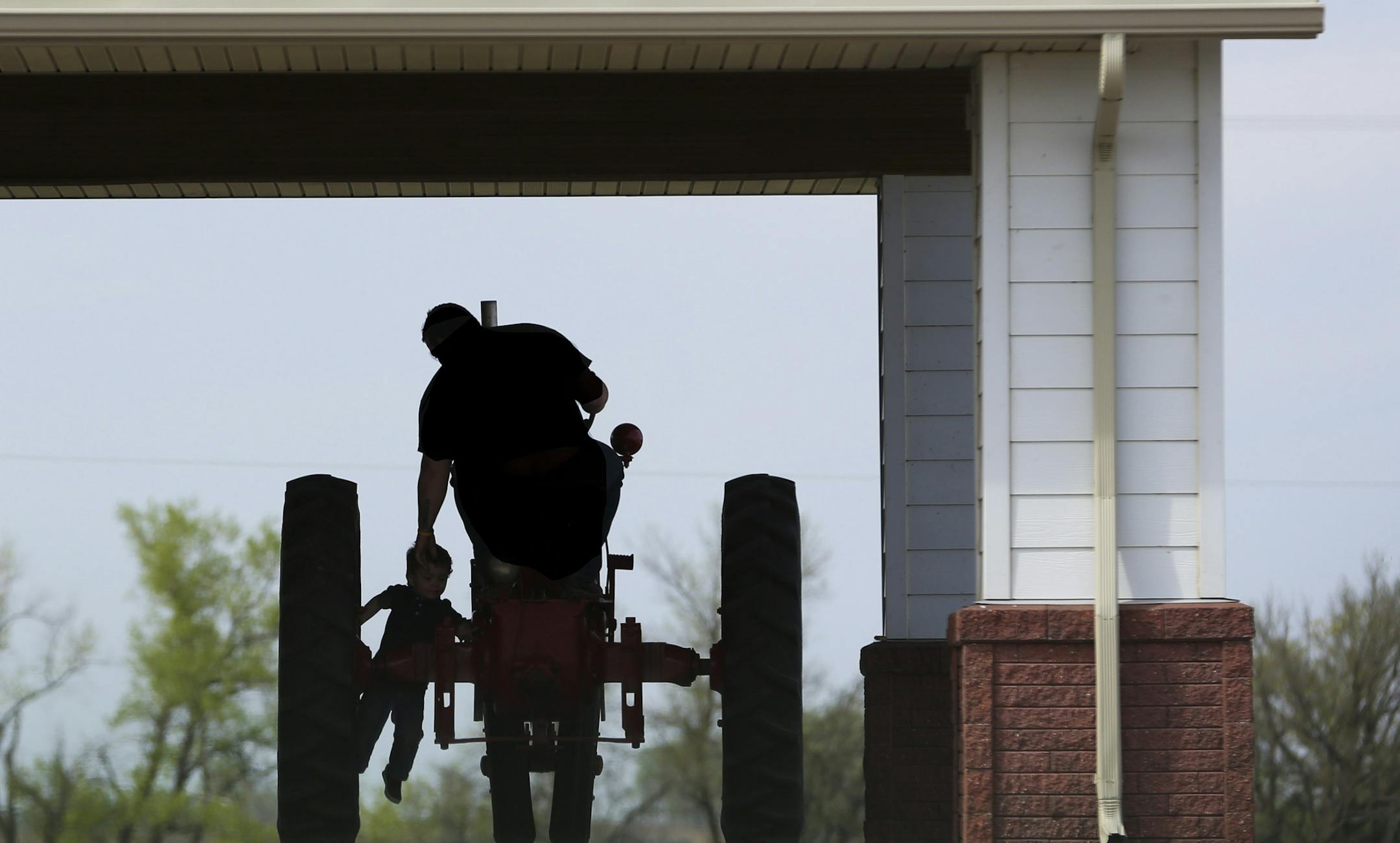 A man gave a hand to a little boy as he climbed up onto a tractor that was place outside the visitation for farmers Jim and Cathy Lively who were killed last week by an intruder. Photographed on Monday, May 4, 2015,in Balaton, Minn. ] RENEE JONES SCHNEIDER ï reneejones@startribune.com ORG XMIT: MIN1505041640120846