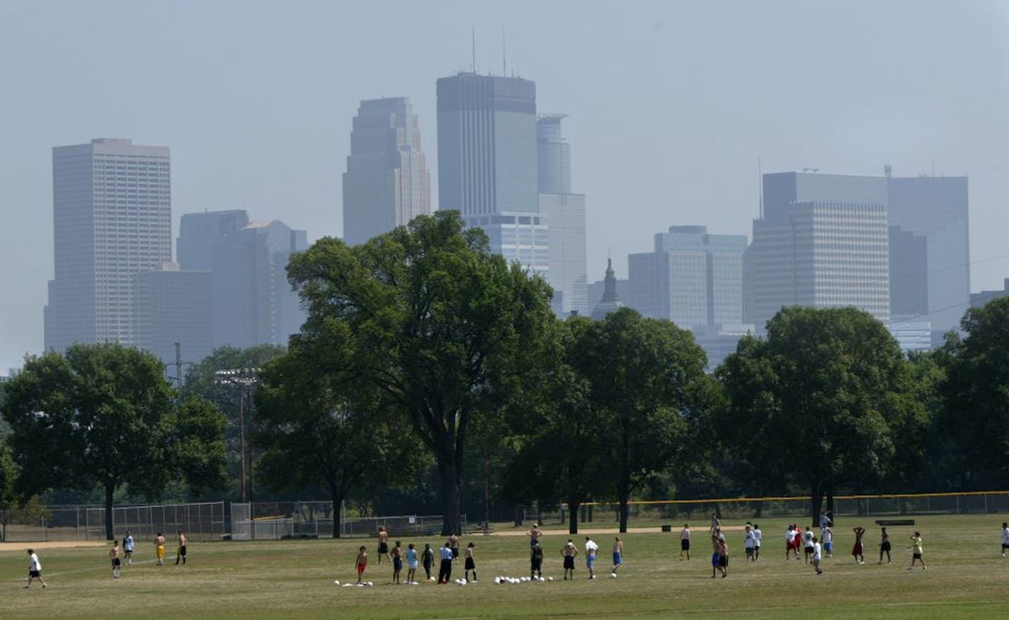 As a member of the De LaSalle soccer squad practice in Penn Park, the Minneapolis skyline is hazy behind him Friday as pollution levels reach the precautionary levels due to heat and lack of rain in the Twin Cities.