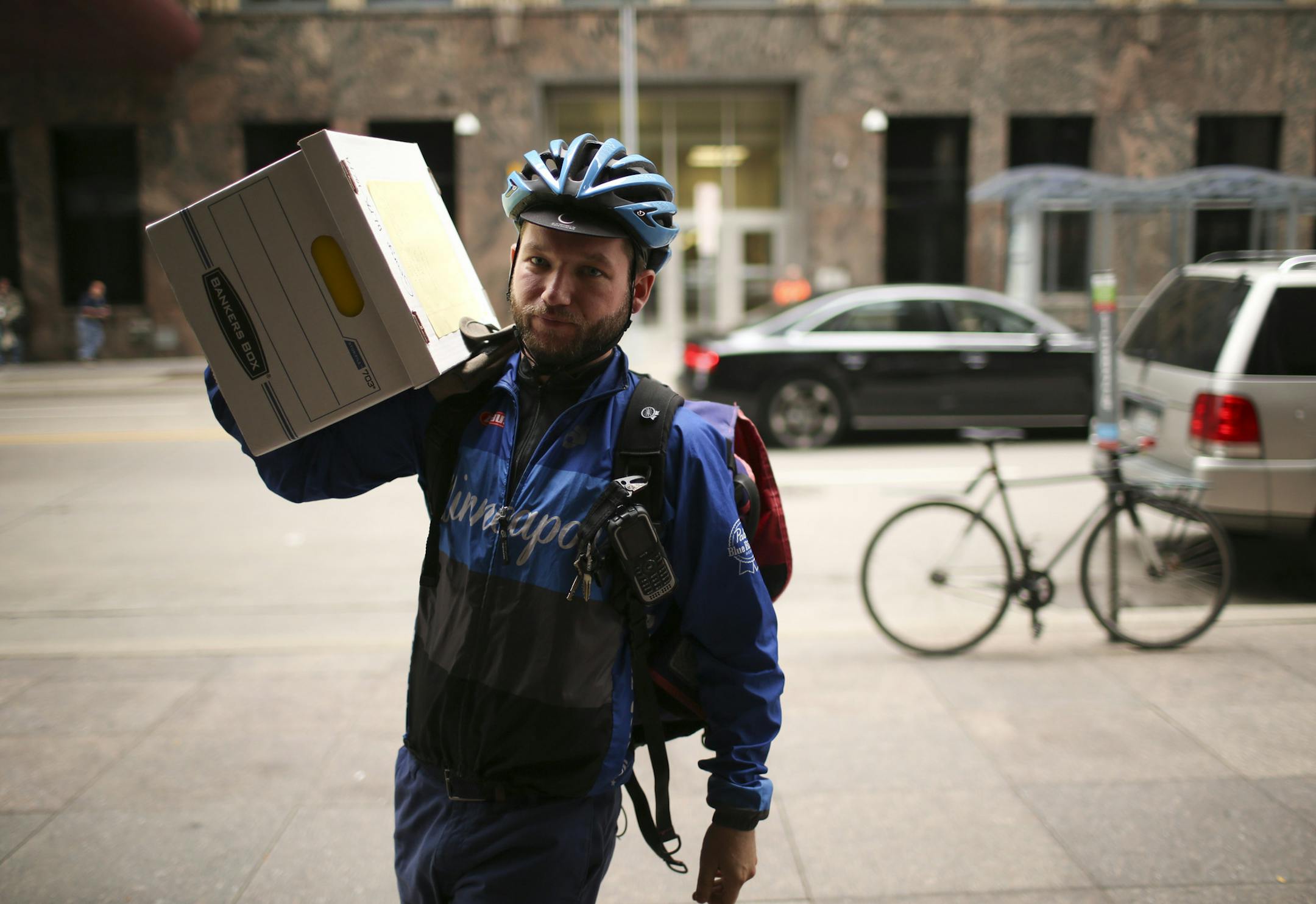 Messenger Jeff O'Neill carried a box of documents from his bicycle, rear, for delivery to an office in downtown Minneapolis Wednesday afternoon. ] JEFF WHEELER • jeff.wheeler@startribune.com Digital document delivery hasn't completely eliminated the career of the bike messenger, but the numbers of people making a living at it are fewer. Jeff O'Neill is one of three bike messengers working for Metro Legal Services in downtown Minneapolis. He was photographed Wednesday, August 19, 2015 on a