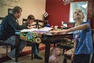 Asher,7, plays with his sister, Sabriella,2, while Alex Kempe helps oldest son Aiden,9, with his math homework.