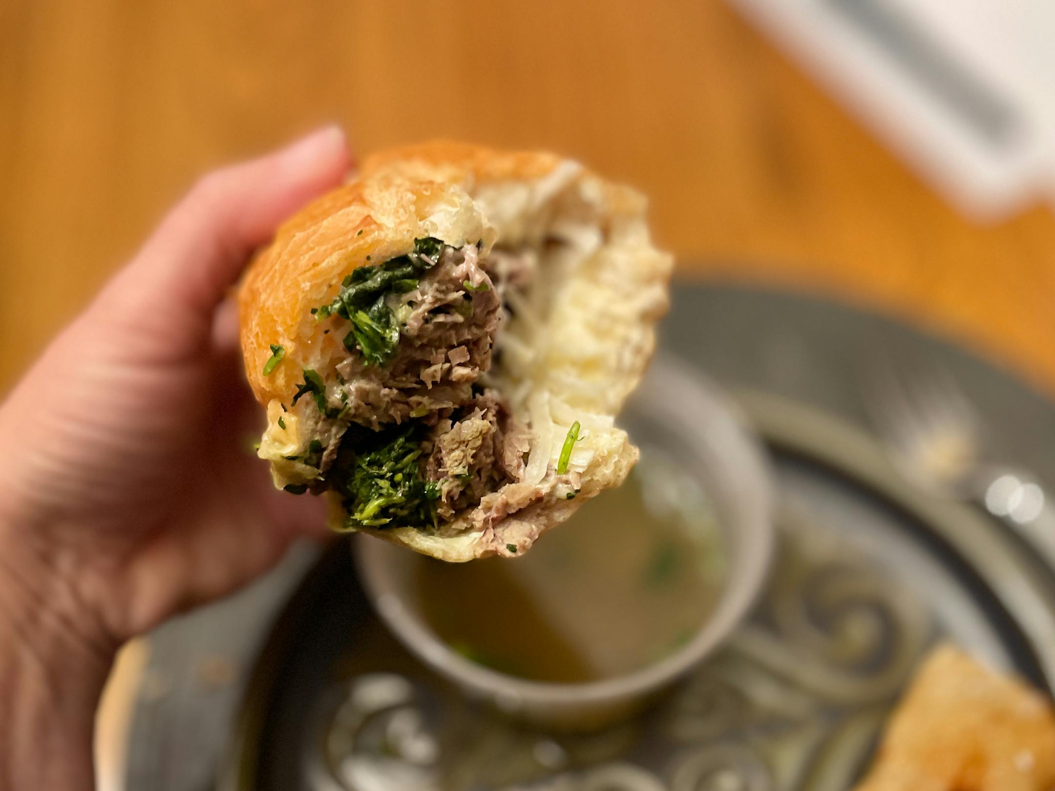 Thinly sliced ribeye, braised greens, shaved onions on a crusty baguette with  a bowl of pho broth for dipping at Grand Avenue's Em Que Viet.
