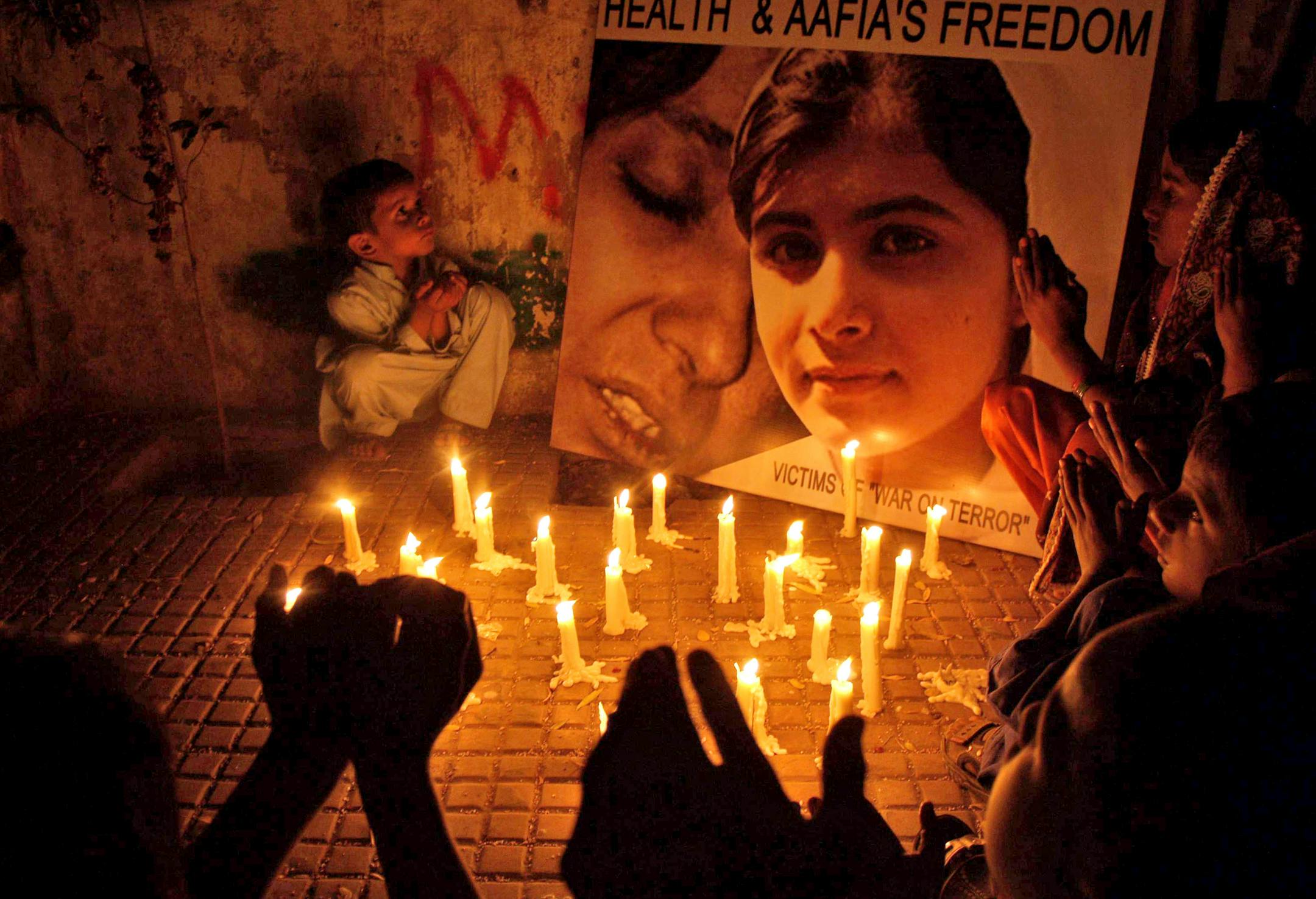 Pakistani children sit around a picture of 14-year-old schoolgirl Malala Yousufzai, who was shot last Tuesday by the Taliban for speaking out in support of education for women, as they pray for her recovery during a candlelight vigil in Hyderabad, Pakistan, Saturday, Oct. 13, 2012. (AP Photo/Pervez Masih)