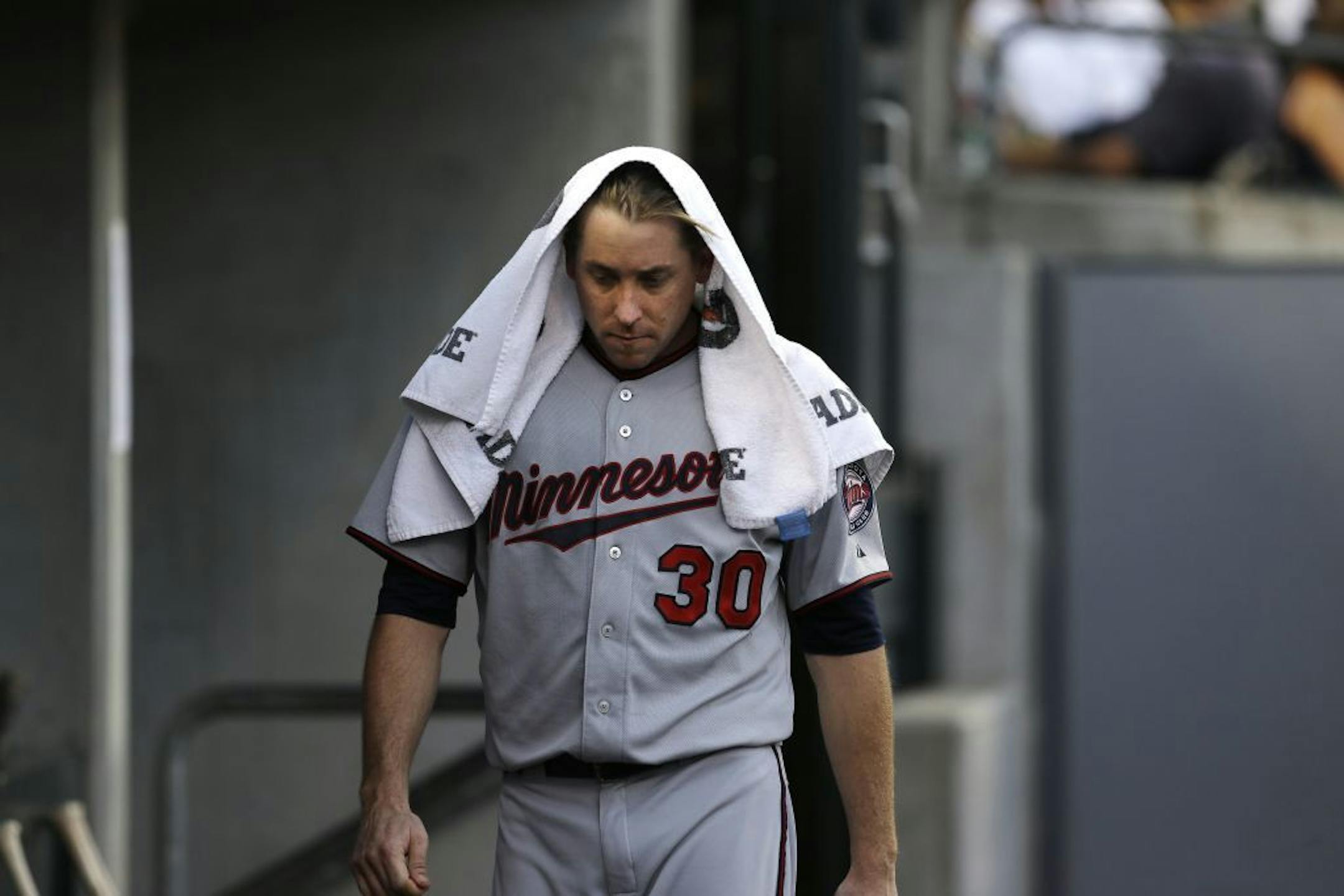 Minnesota Twins starting pitcher Kevin Correia walks in the dugout against the Detroit Tigers in the third inning of a baseball game in Detroit, Wednesday, Aug. 21, 2013.