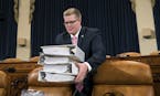 Copies of the proposed Republican tax package are carried by House Ways and Means Committee staffer Thomas Kutz before the start of the markup session