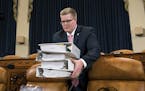 Copies of the proposed Republican tax package are carried by House Ways and Means Committee staffer Thomas Kutz before the start of the markup session