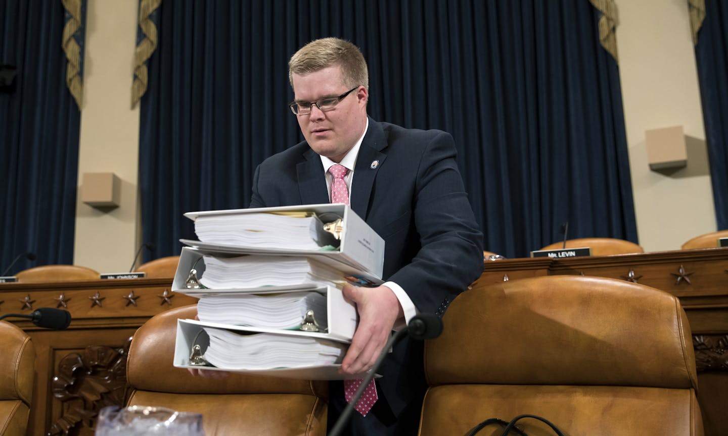 Copies of the proposed Republican tax package are carried by House Ways and Means Committee staffer Thomas Kutz before the start of the markup session on the bill, on Capitol Hill in Washington, Monday, Nov. 6, 2017. The House tax-writing committee is kicking off debate today on a 429-page GOP tax overhaul plan in hopes of having it ready for a vote by the full House next week. (AP Photo/J. Scott Applewhite)