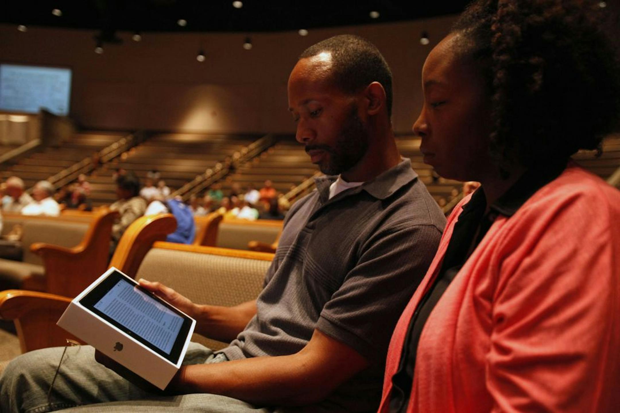Jacques James and his wife, Christa, followed along with their Bible iPad app for the first time during a Bible study in July at Apostolic Church in Auburn Hills, Mich. Some e-versions of the Bible offer maps, audio and video renderings of Scripture and allow readers to compare translations side by side.