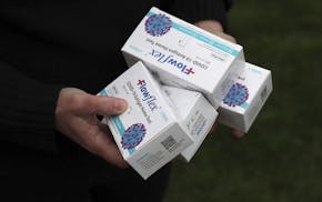 Teena McClelland holds four boxes of COVID tests outside of her home on April 28, 2022, in Chicago. McClelland has spent nearly a month trying to get