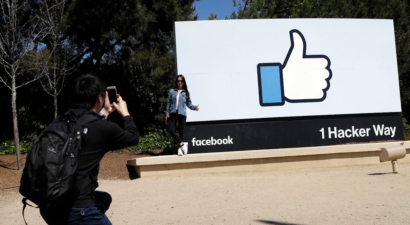 FILE- In this March 28, 2018, file photo, visitors take photos in front of the Facebook logo at the company's headquarters in Menlo Park, Calif. Facebook reports earnings Wednesday, April 25. (AP Photo/Marcio Jose Sanchez, File)