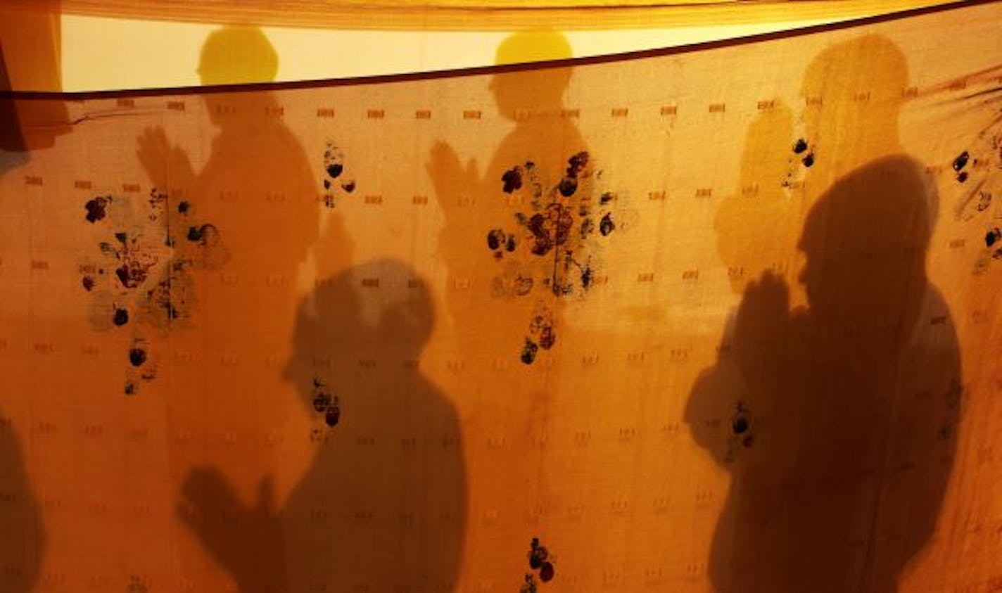 Shadows of Hindu devotees praying on the bank of the River Ganges in Allahabad, India.