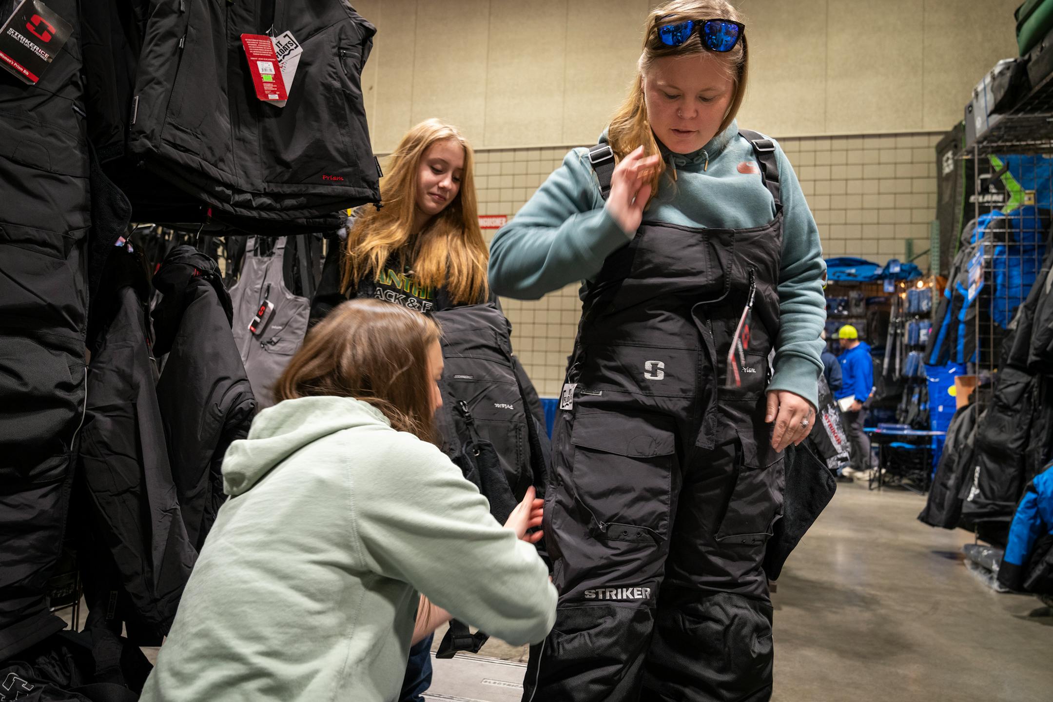 Kayla Quarders of Prairie Farm, Wis.tries on a pair of Striker bibs at the St. Paul Ice Fishing and Winter Sports Show in St. Paul, Minn. Friday, Dec. 1, 2023. ] LEILA NAVIDI • leila.navidi@startribune.com
