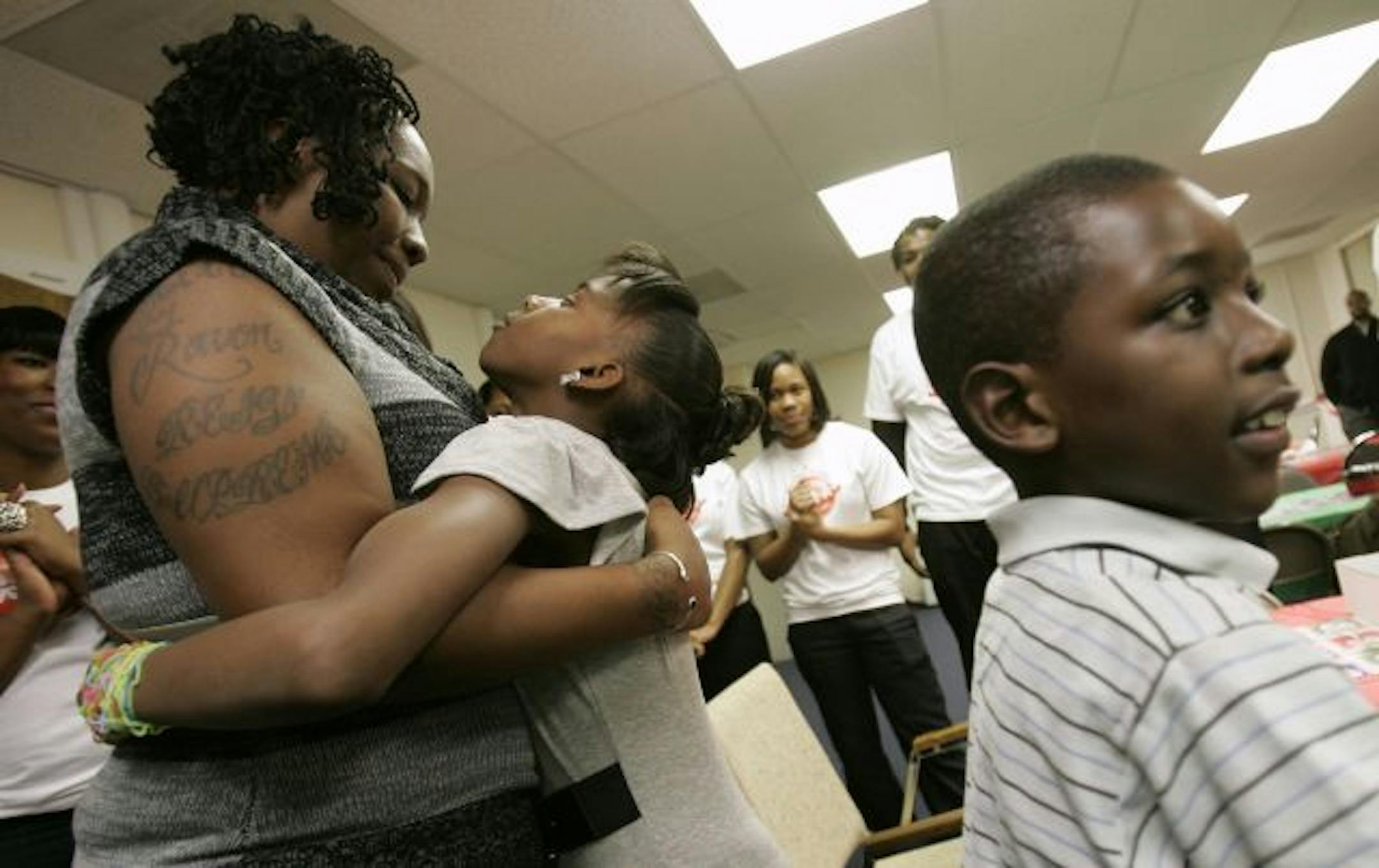 SPECIAL TO MINNEAPOLIS STAR TRIBUNE-- Danielle Scott, left, gets a hug from her daughter Ravonne 9, as her son Deamondre 7, looks at a pile of Christmas presents that Charde Houston, a basketball player with the Minnesota Lynx of the WNBA, bought the family of six at the Youth Advocate Program office in Atlantic City, N.J. on Wednesday, Dec. 22, 2010. Houston's foundation, Project Youth Opportunities Unlimited, raised the money in conjunction with the Youth Advocate Program of Atlantic County. T