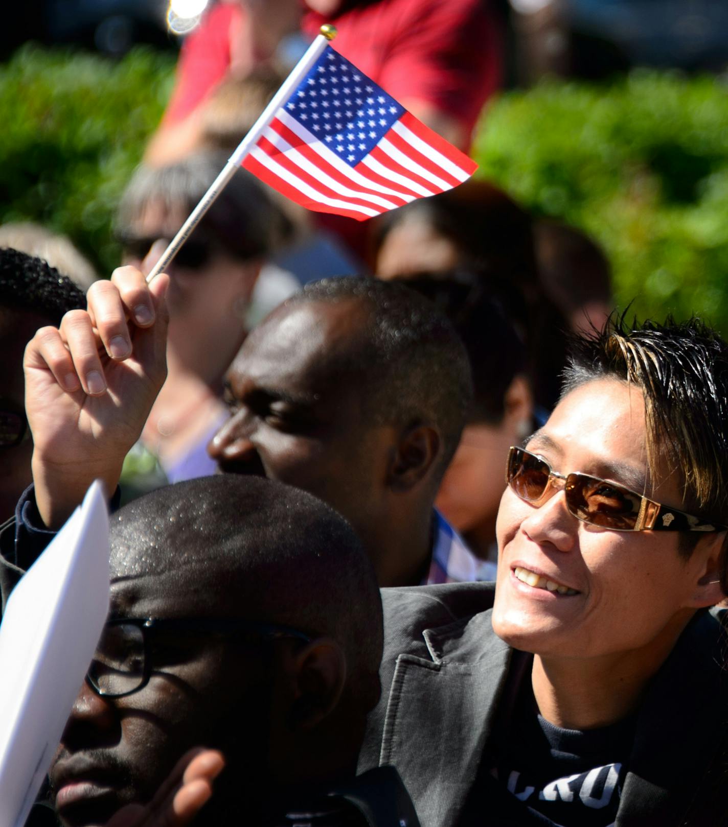 New citizen Anthony Pham from Vietnam waved an American flag as a recording of Lee Greenwood's song Proud to be an American played. 135 immigrants were sworn in as U.S. citizens today, Friday June 13, 2014, at the Harriet Island Pavilion overlooking the banks of the Mississippi River. ] GLEN STUBBE * gstubbe@startribune.com