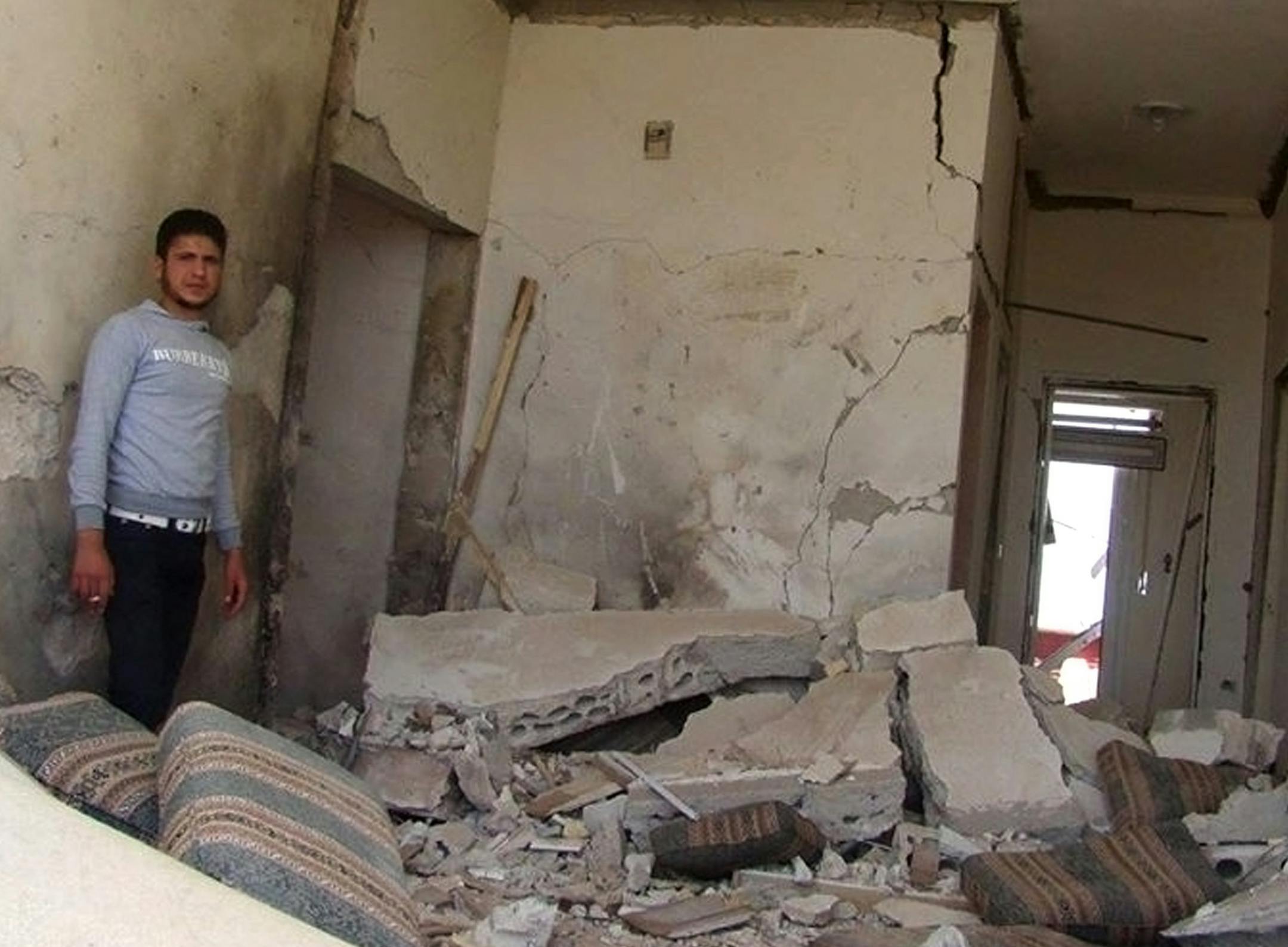 This citizen journalism image provided by Edlib News Network, ENN, which has been authenticated based on its contents and other AP reporting, shows a Syrian man checking his destroyed house that was damaged by a Syrian forces air strike, in Idlib province, northern Syria, Thursday, June 13, 2013. (AP Photo/Edlib News Network ENN)