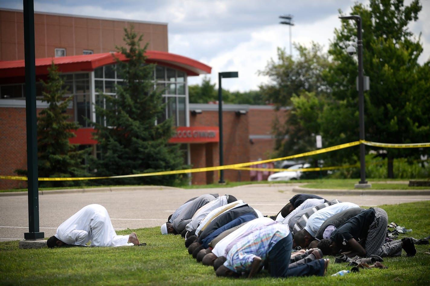 Mohamed Omar, left, the executive director of the Dar Al Farooq Islamic Center in Bloomington, leads the afternoon prayers outside the police tape surrounding the center Saturday.
