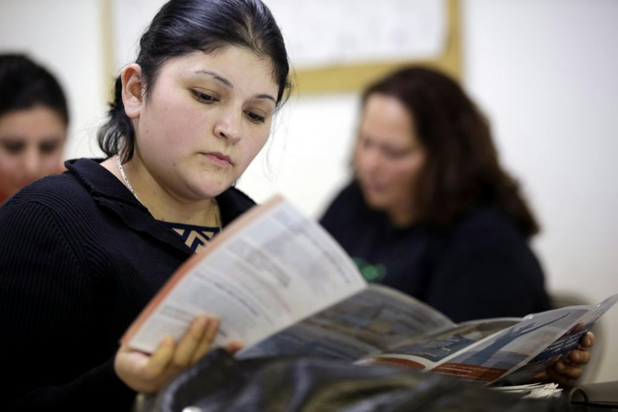 In this Tuesday, March 11, 2014 photo, Sara Rodriguez looks over an Affordable Care Act brochure, in Houston. Rodriguez, like others who gathered to listen to a presentation about President Barack Obama�s signature health care overhaul, says she can�t afford insurance, even for $50 a month.