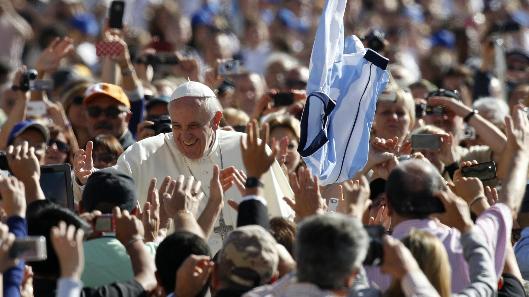 A faithful tosses in the air a jersey with the colors of the Argentine flag as Pope Francis greets faithful upon arrival for his weekly general audience in St. Peter's Square at the Vatican, Wednesday, Sept. 18, 2013. (AP Photo/Riccardo De Luca)