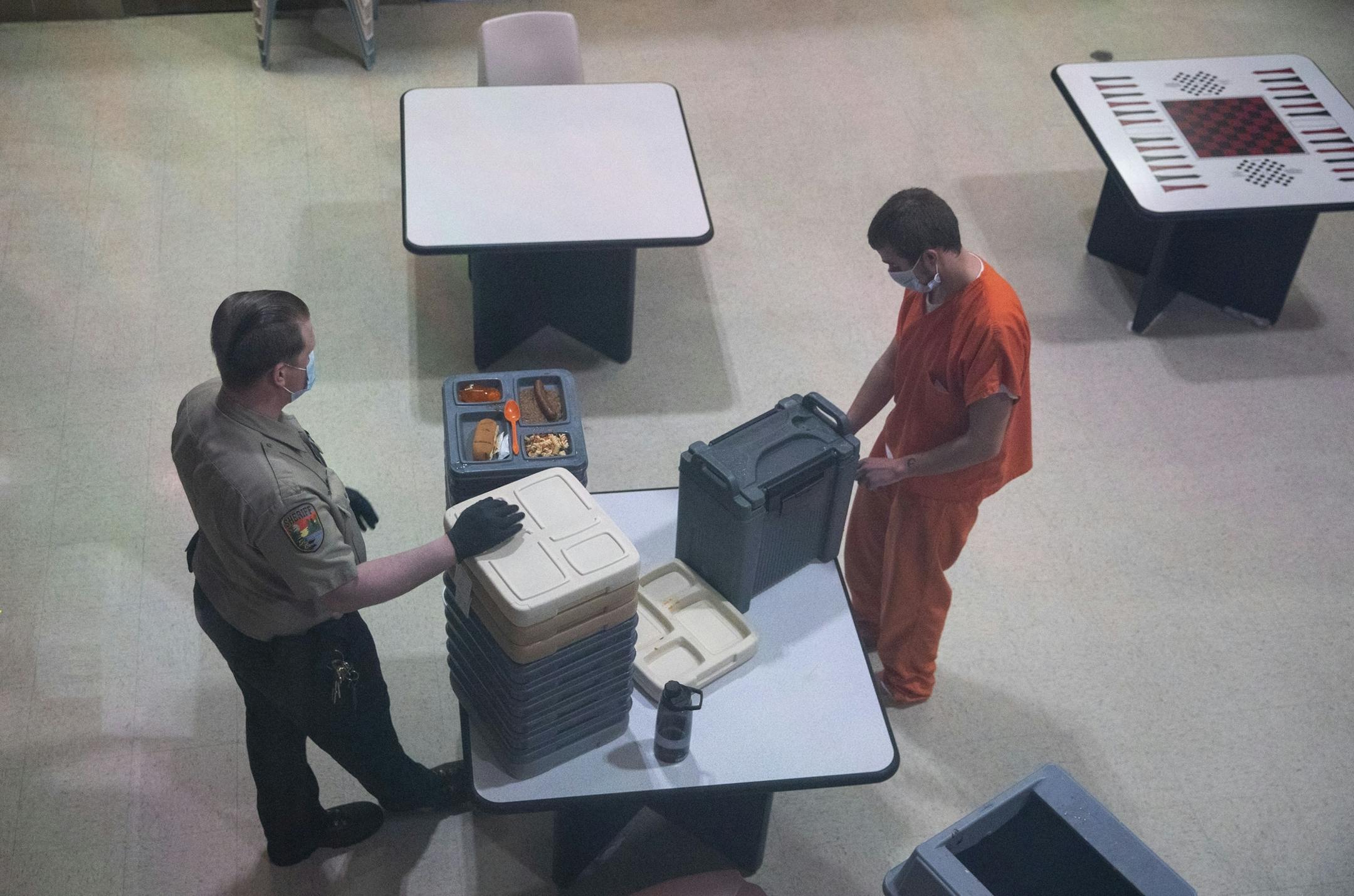 New inmates in an observation cell block exited their cell one or two at a time and donned face masks to receive their lunch trays at St. Louis County jail on Tuesday.